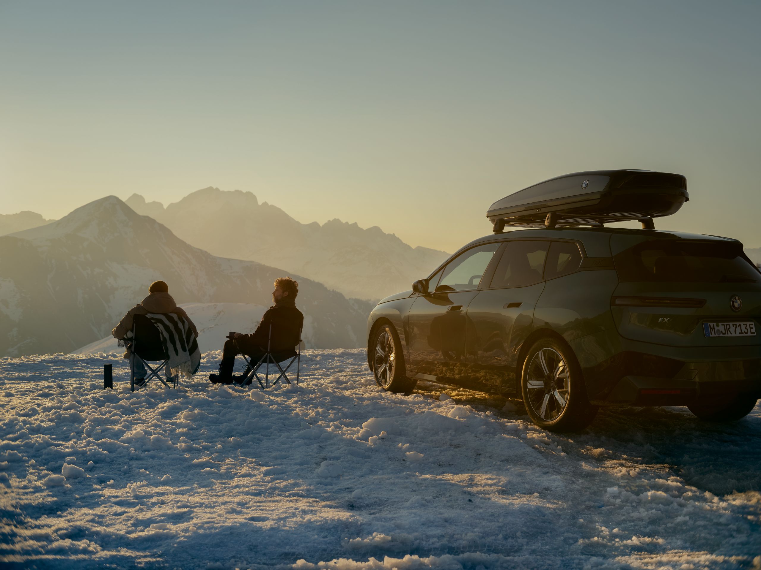  Zwei Männer sitzen im Schnee vor einem BMW.