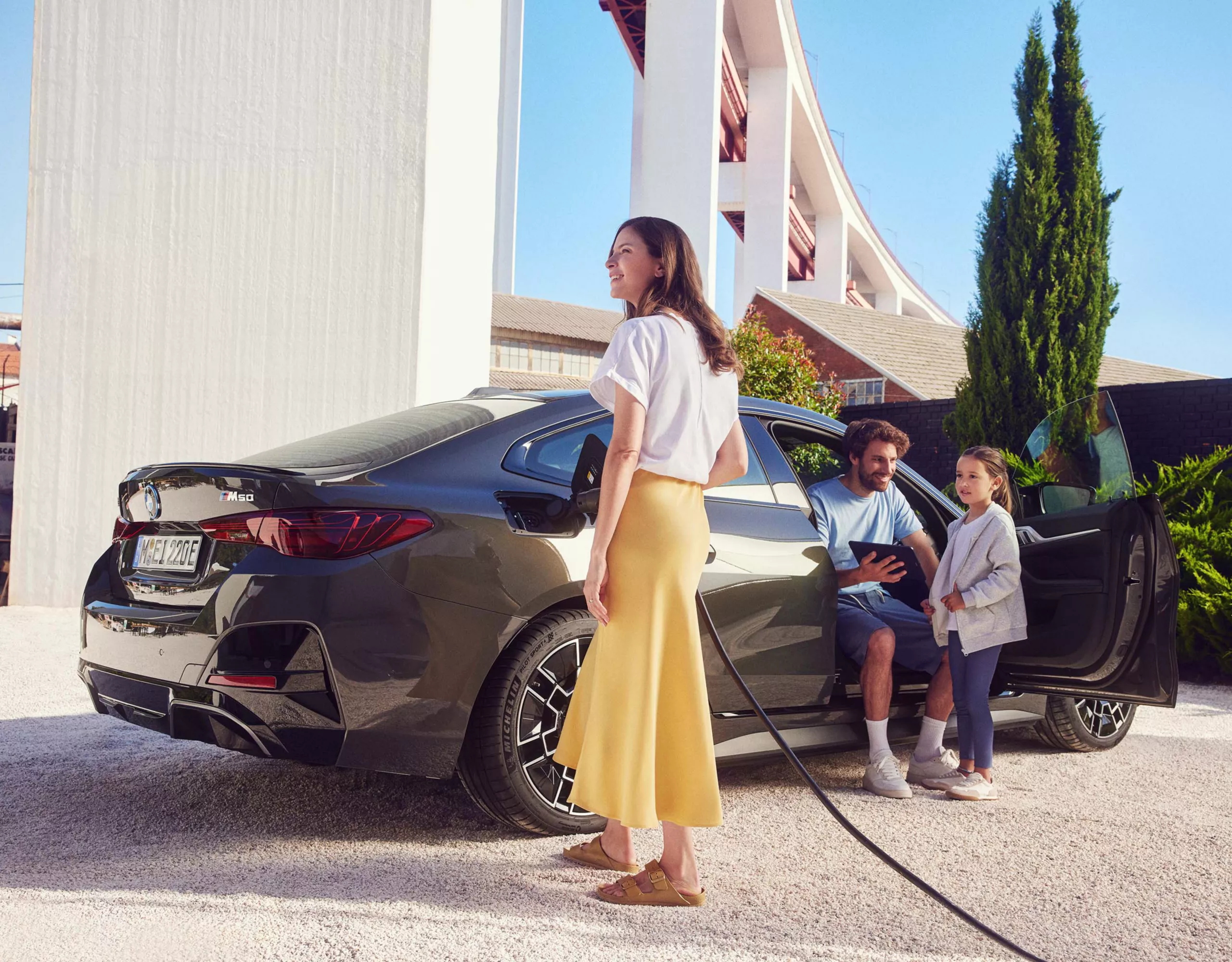 BMW i4 snett bakifrån med en man, kvinna och barn bredvid