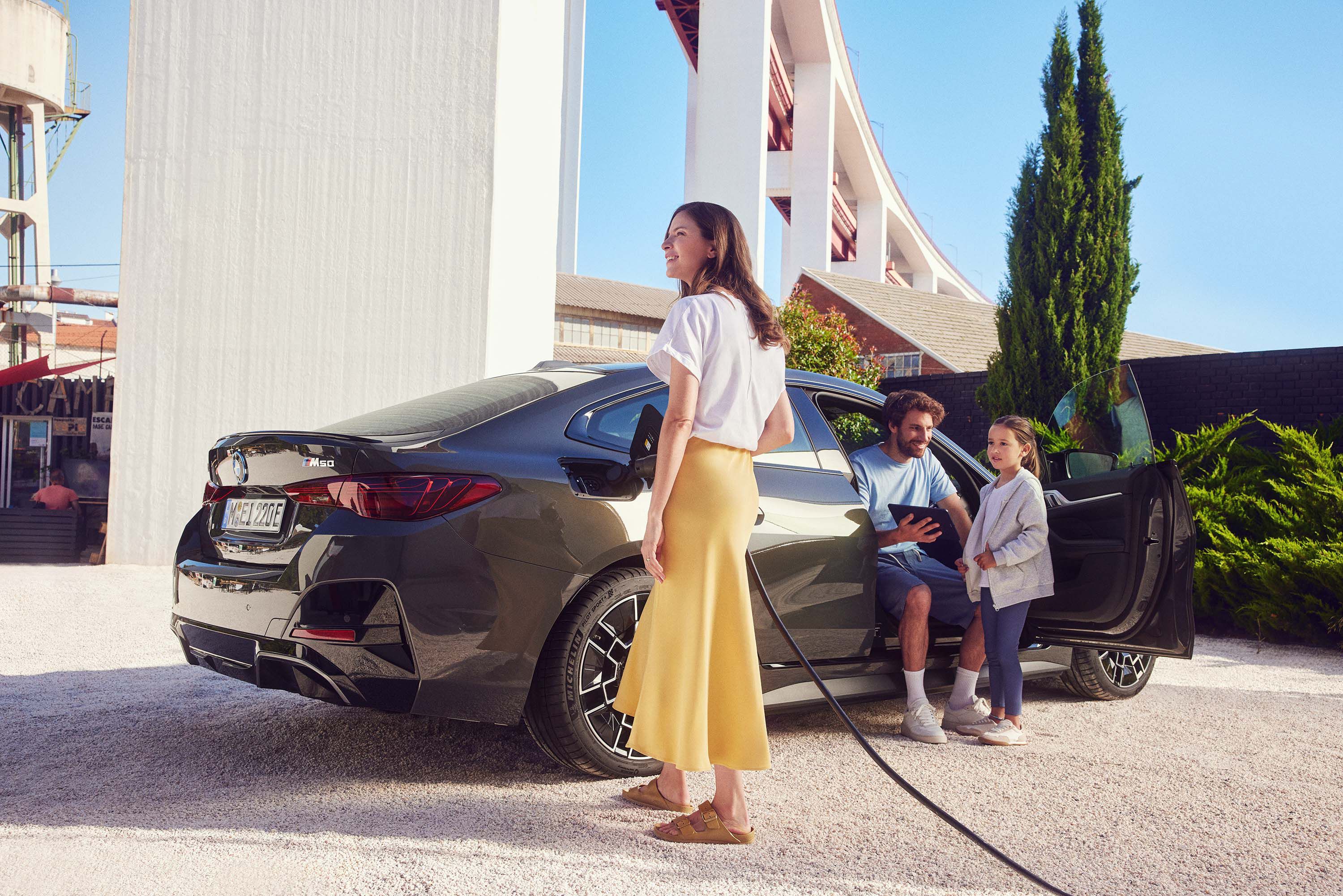 BMW i4 snett bakifrån med en man, kvinna och barn bredvid