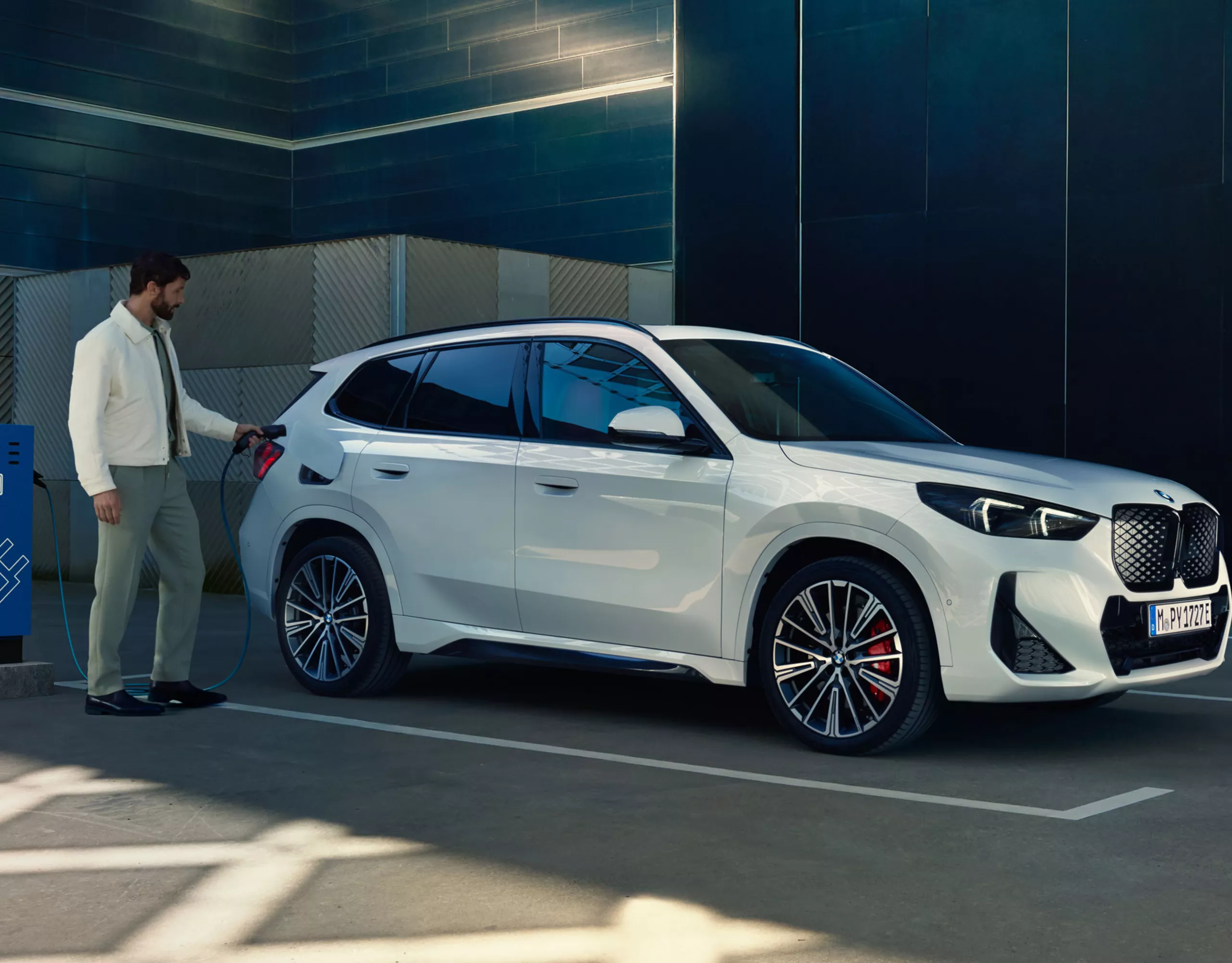 BMW iX1 snett från sidan som laddas av en man