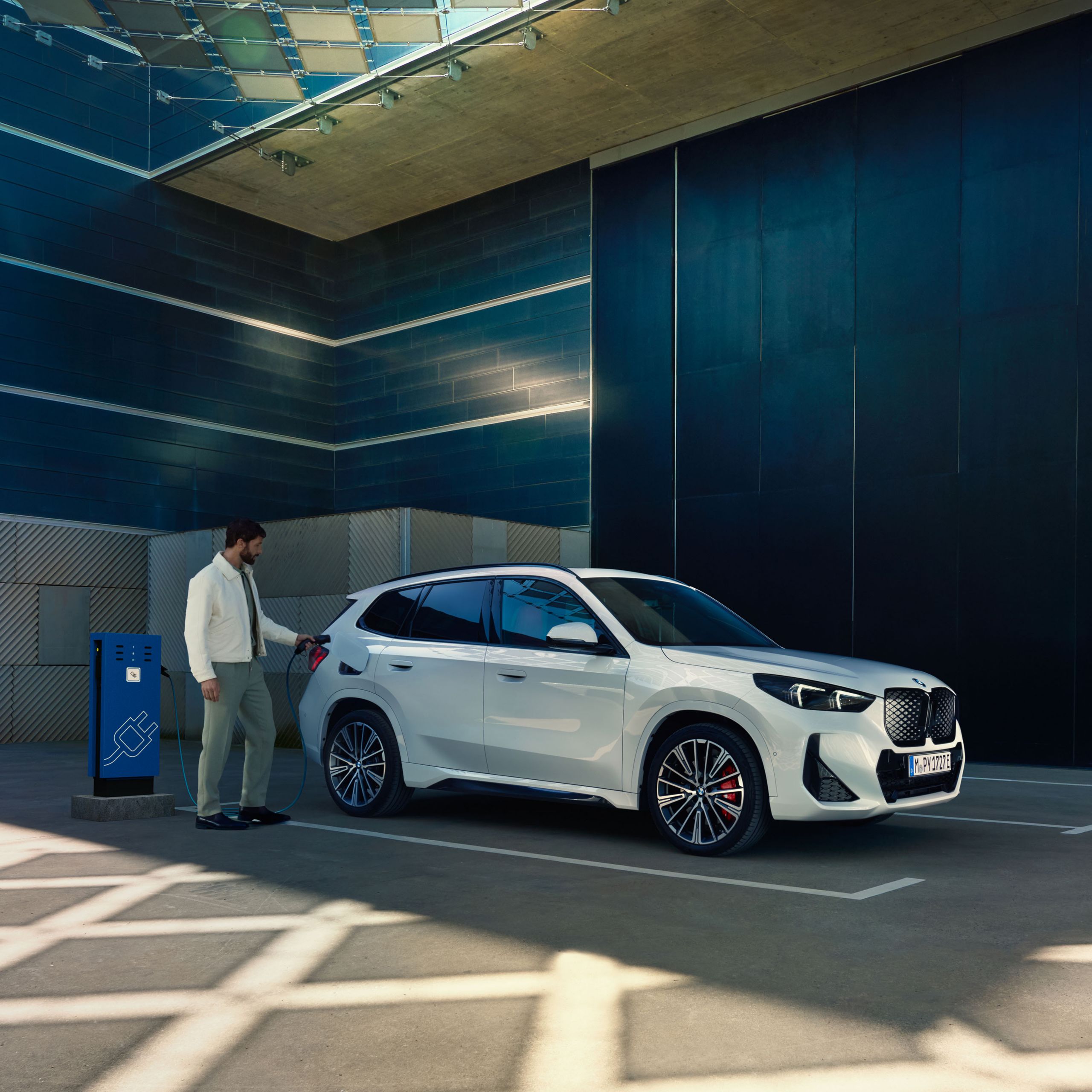 BMW iX1 snett från sidan som laddas av en man