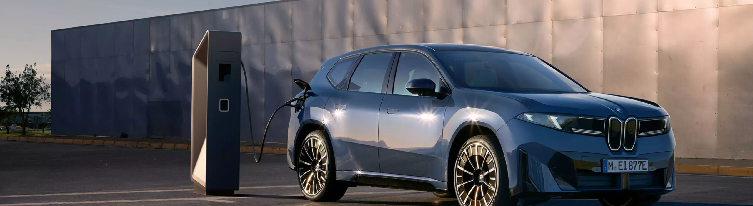 Sininen BMW iX3 parkkeerattuna latauksessa. 