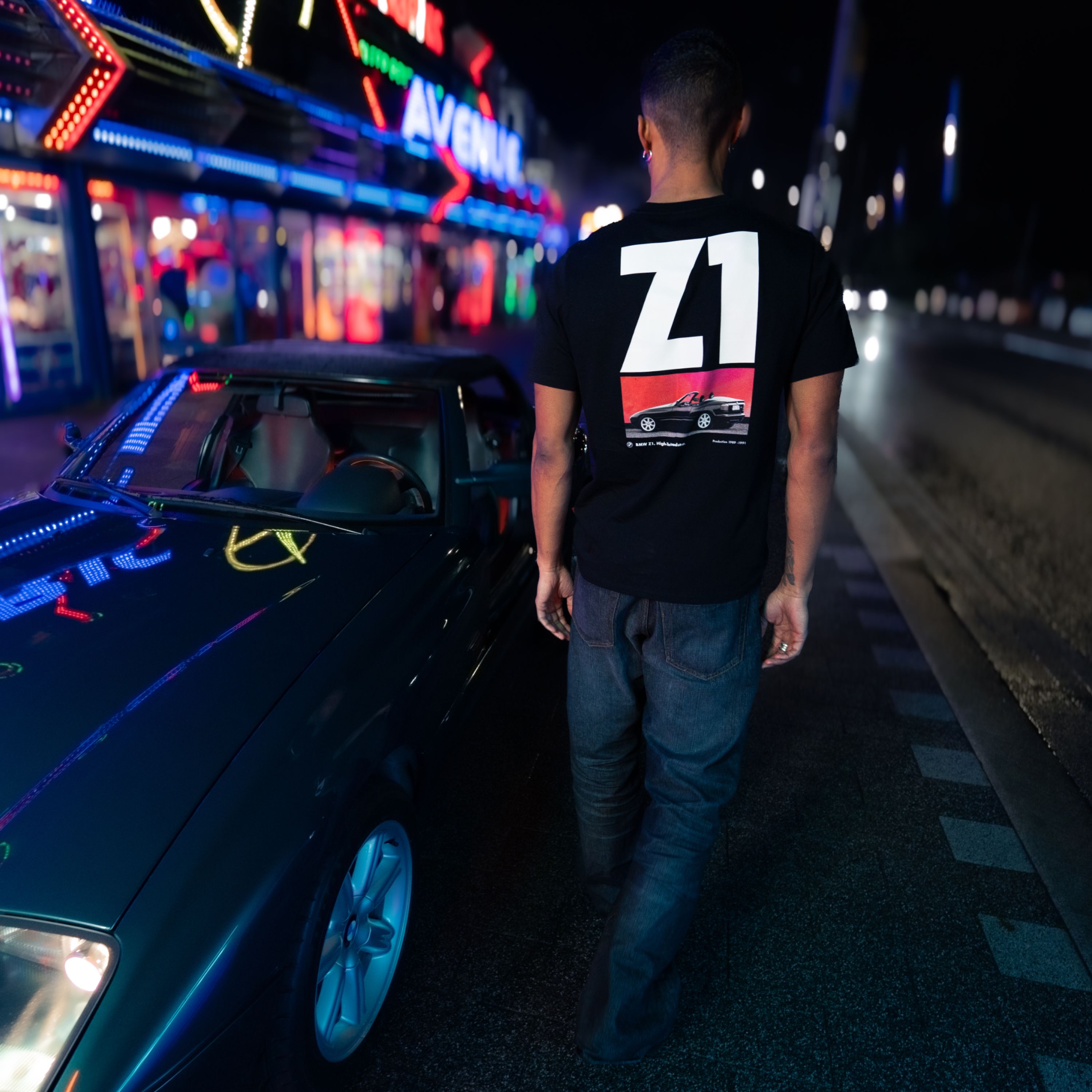 Maglietta BMW Lifestyle in nero con grande scritta Z1 bianca sul retro al di sopra del motivo di una BMW Z1 nera su sfondo rosso