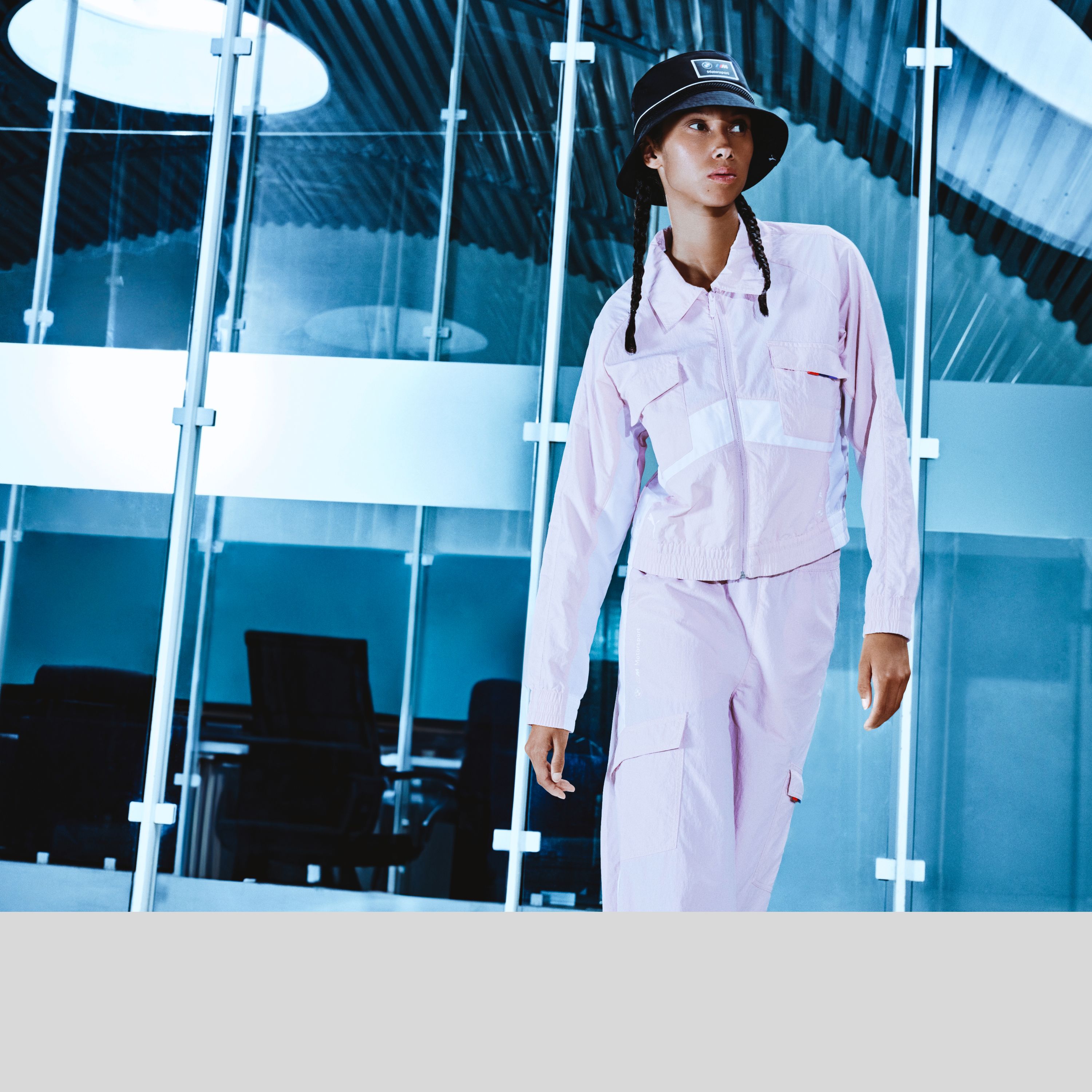 Giacca e pantaloni in Pink Organdy con cappello nero della collezione BMW Lifestyle della collezione BMW M, indossati da un giovane