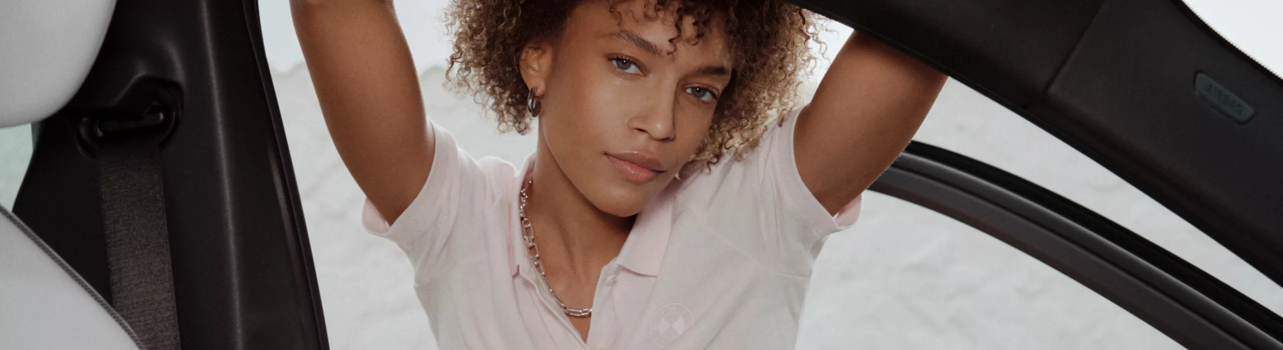 BMW Lifestyle shirt, worn by a young woman leaning against an open car door