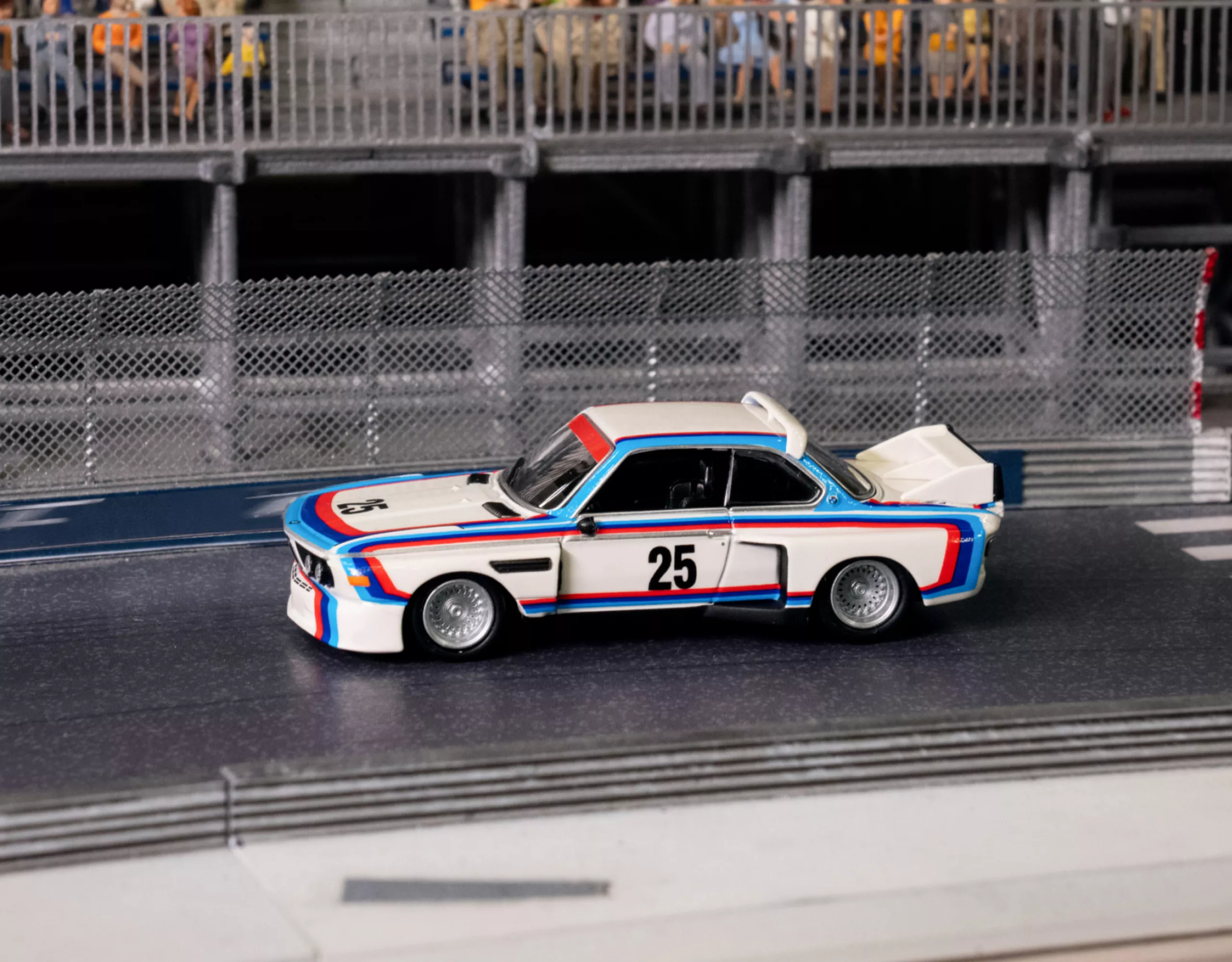 BMW Lifestyle BMW M3 E30 Miniatur mit Seehausstreifen und der Nummer 25 auf der Tür auf einer Miniatur-Rennstrecke