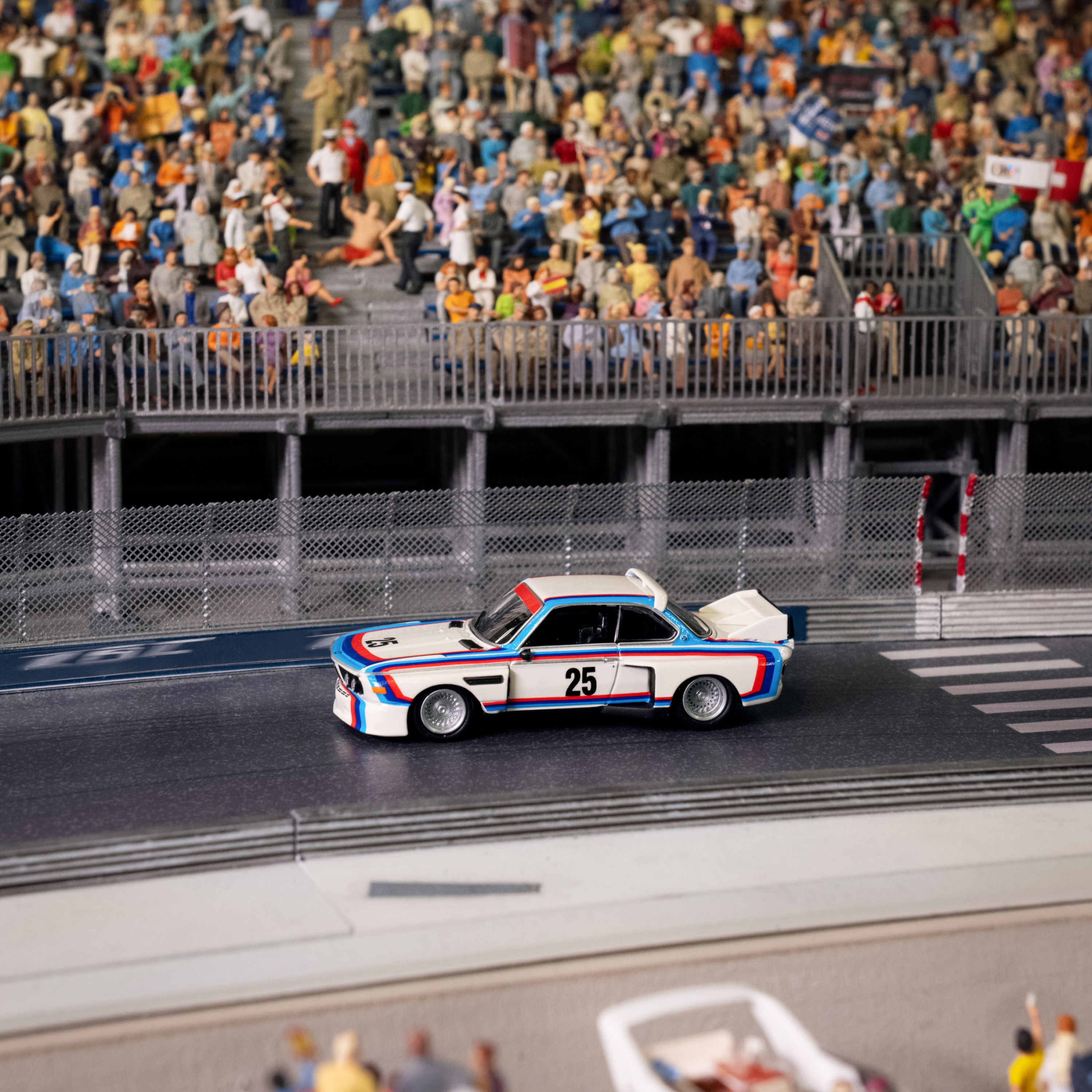 Modellino BMW M3 E30 BMW Lifestyle con strisce Seahaus e numero 25 sulla portiera su un circuito in miniatura
