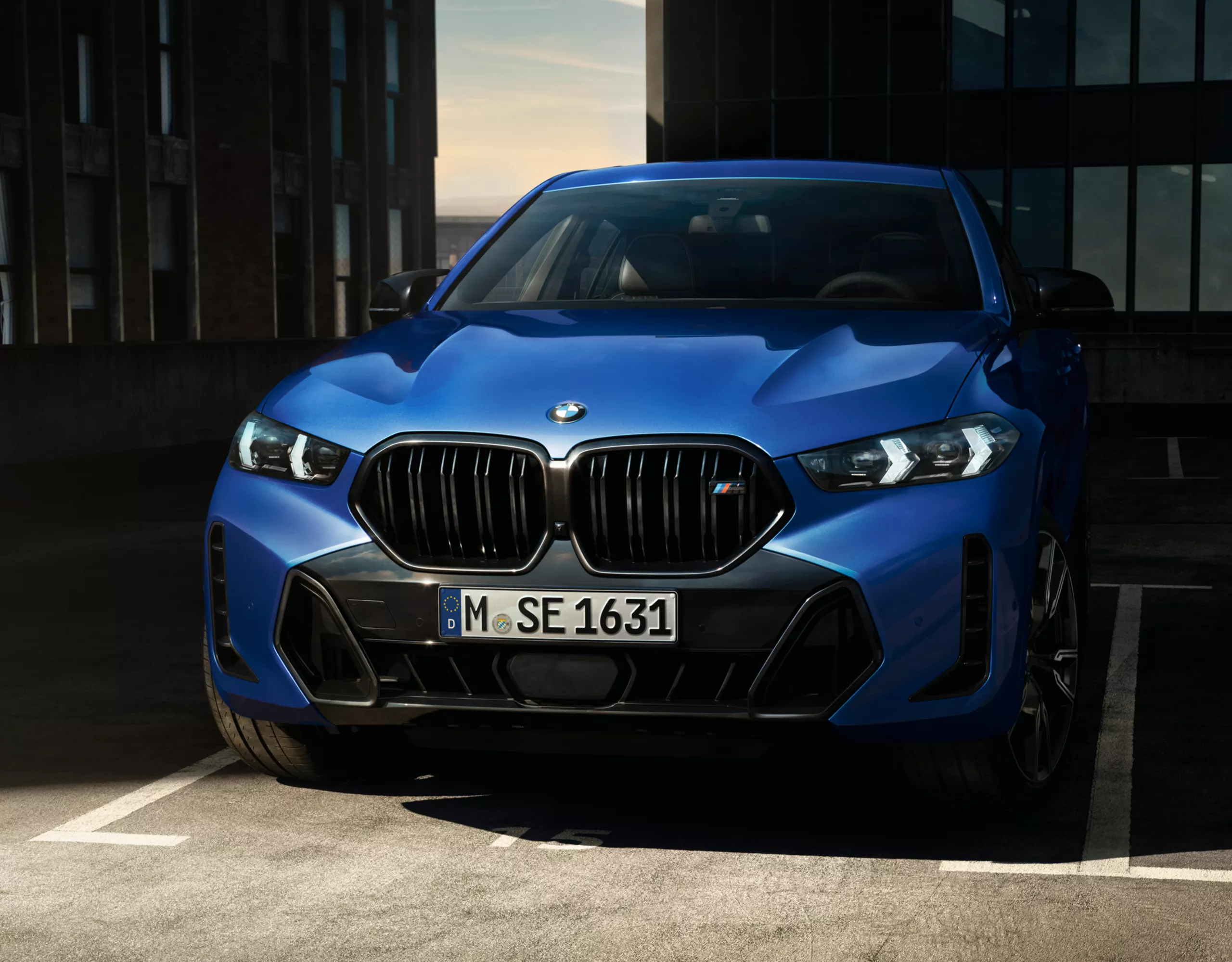 A BMW X6 SUV with M Sport package Pro is parked in front of a hangar door