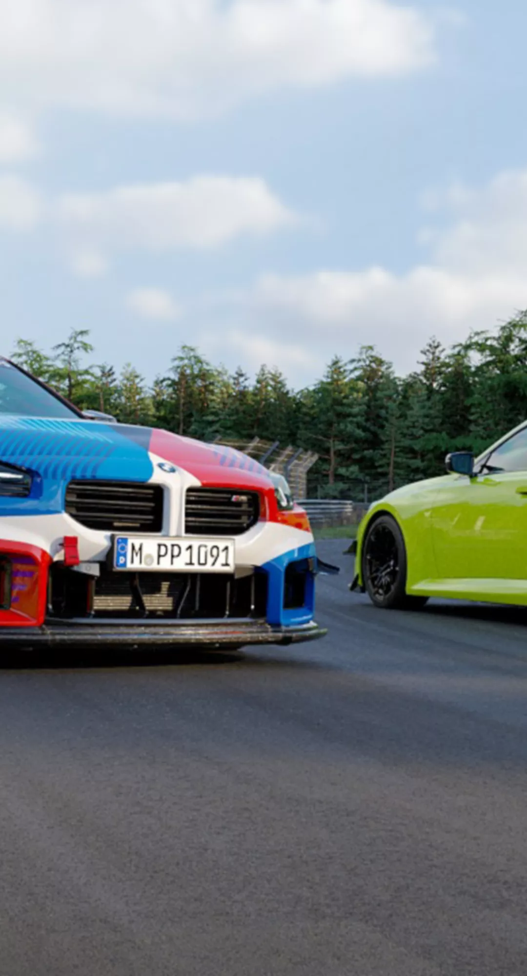 Zwei BMW Sportfahrzeuge nebeneinander auf einer Rennstrecke.