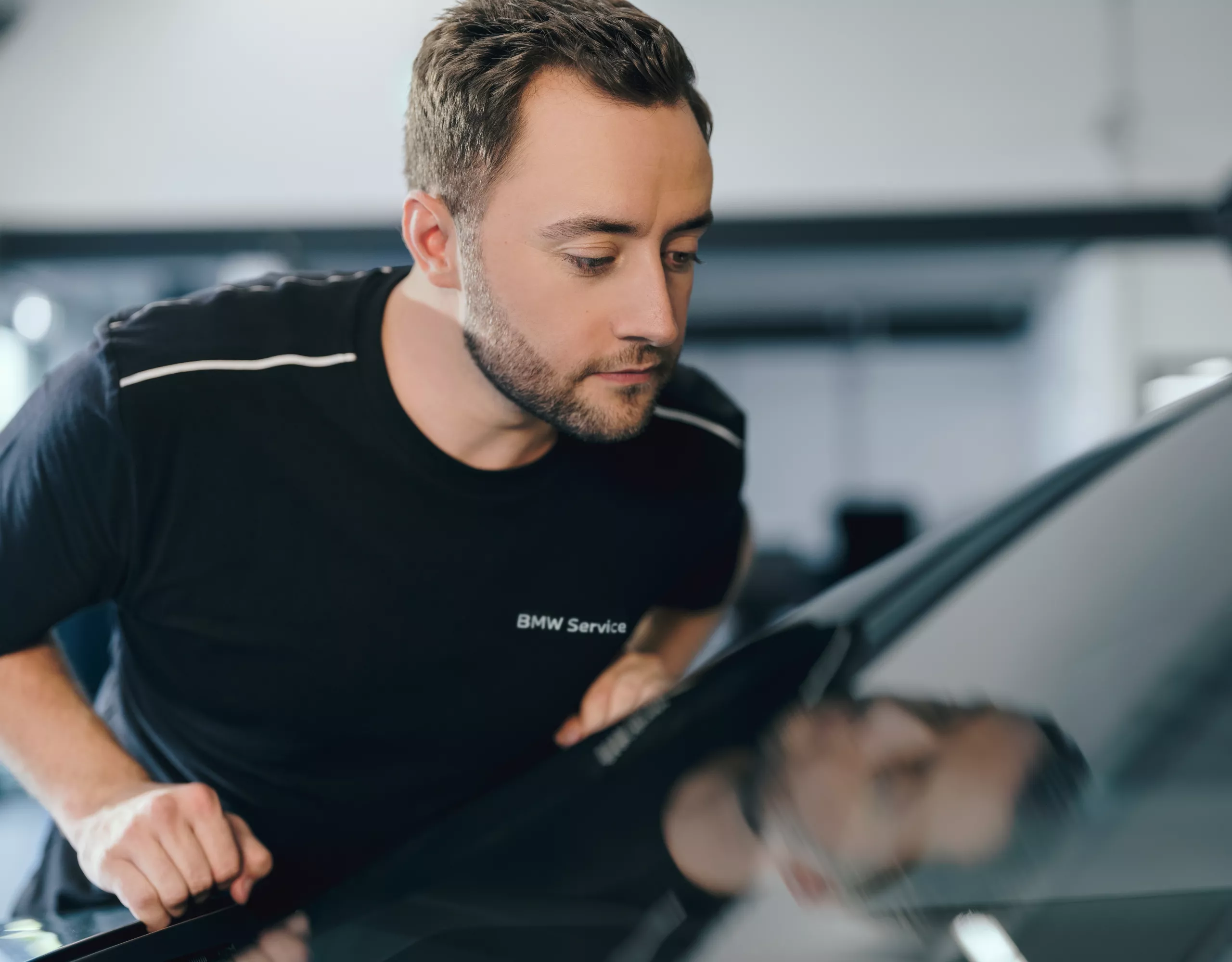 Man and woman stand in front of a BMW looking together at a tablet. A climbing wall can be seen behind the BMW