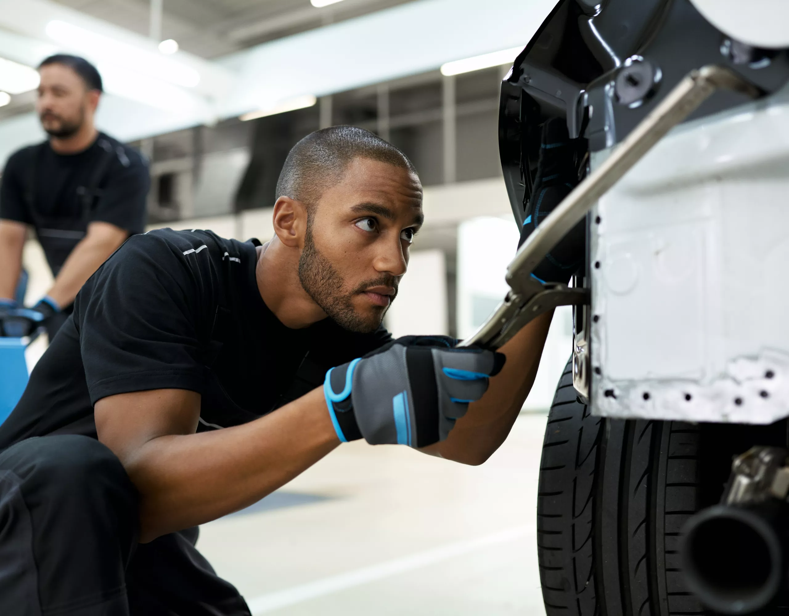 A group of people with backpacks and helmets approach a climbing wall. Next to them is a parked BMW