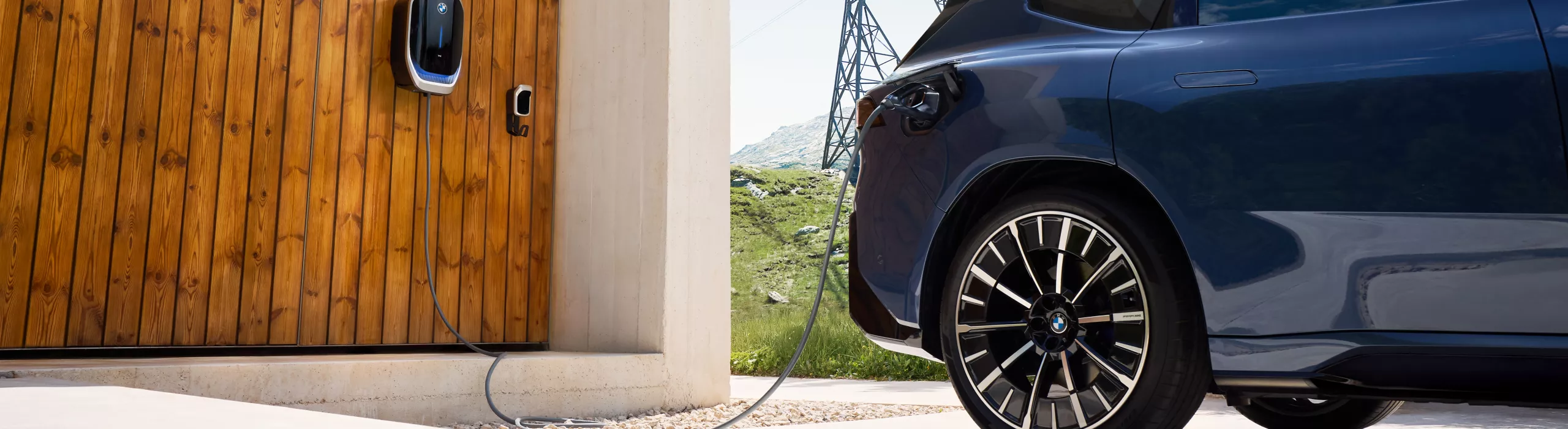Ein BMW iX3 steht vor einem Haus mit Wallbox