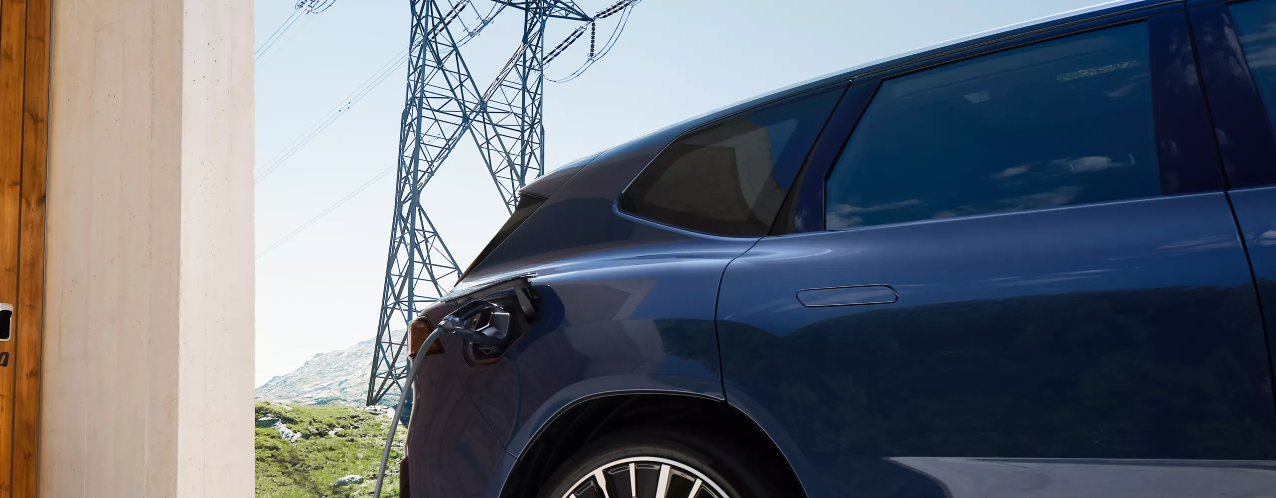 Ein BMW iX3 steht vor einem Haus mit Wallbox