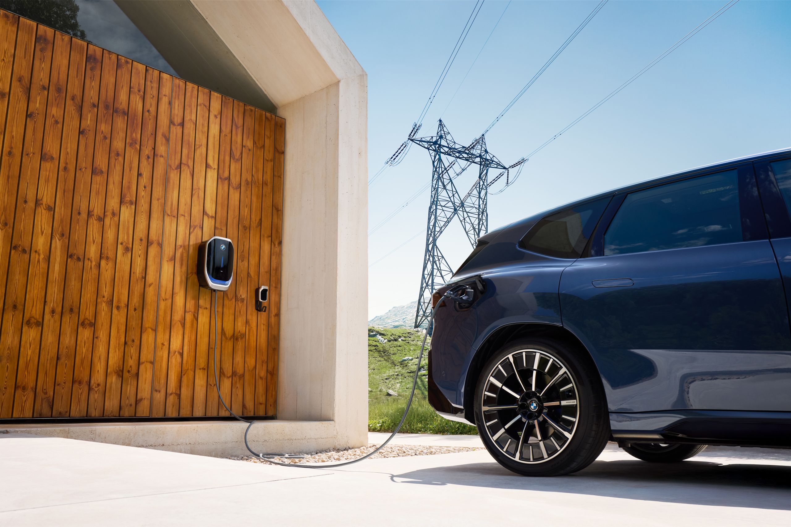 Ein BMW iX3 steht vor einem Haus mit Wallbox