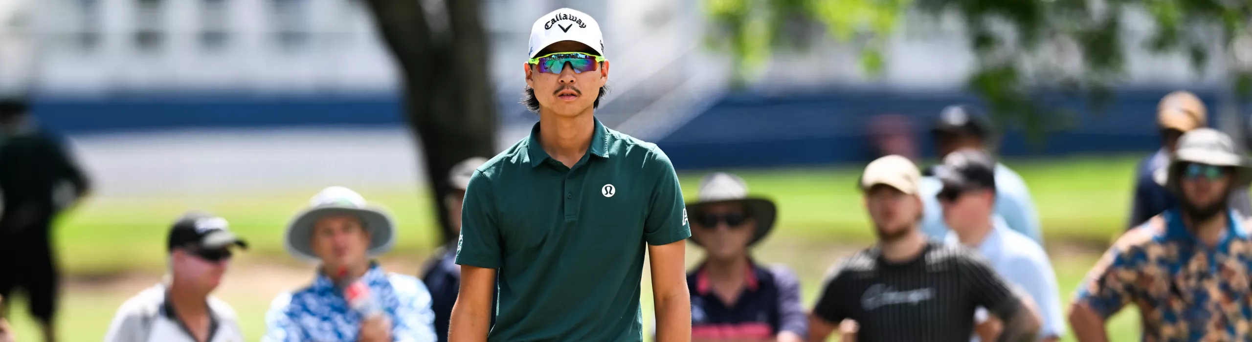 Professional golfer and BMW Australia Golf Ambassador Min Woo Lee of Australia watches his shot on the course at the 2025 BMW Australian PGA Championship . The image captures the athlete in focus in his golf apparel, with an active gallery of spectators and official BMW event branding clearly visible in the background.