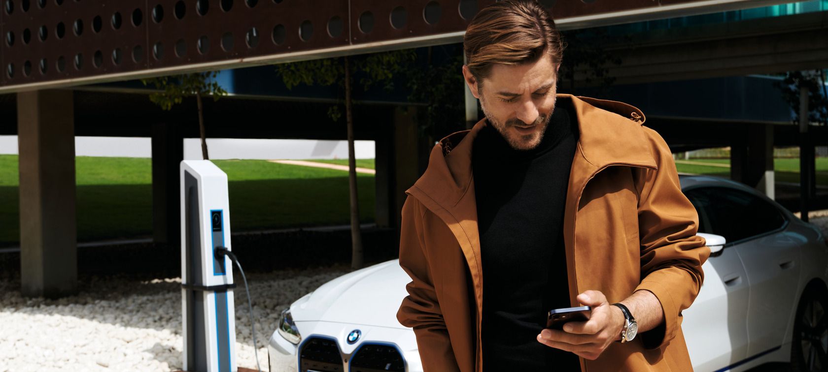 Man in front of BWW iX uses My BMW app on smartphone