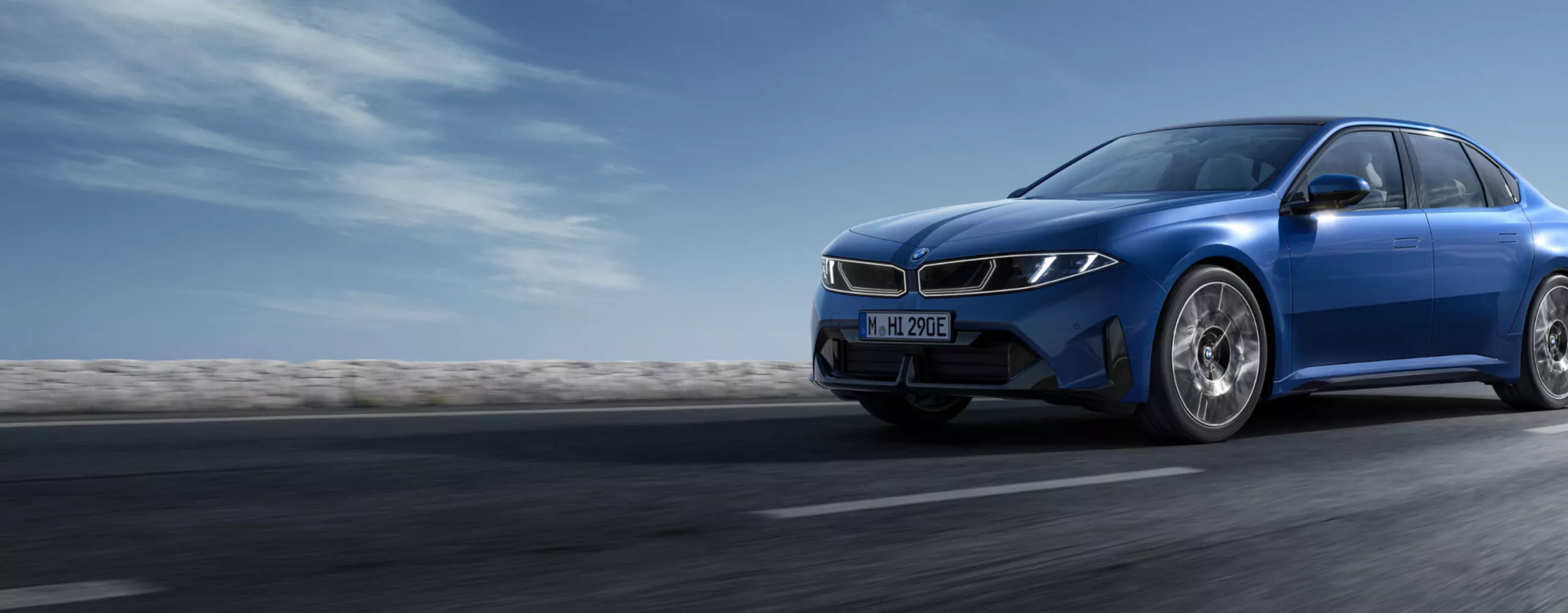 A BMW i3 Sedan is driving on a curvy serpentine road through the mountains