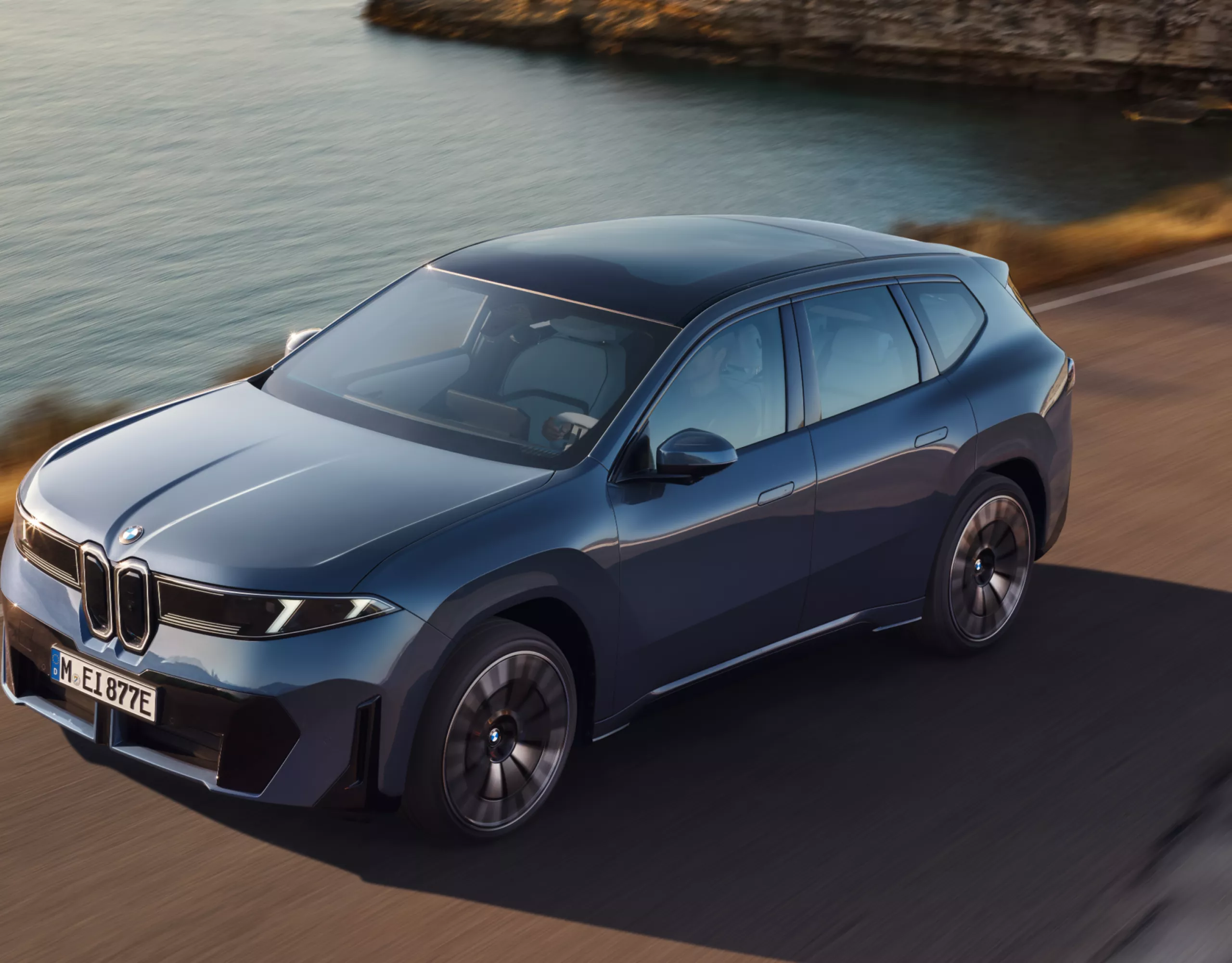 En BMW iX3 kjører på en asfaltert kystvei