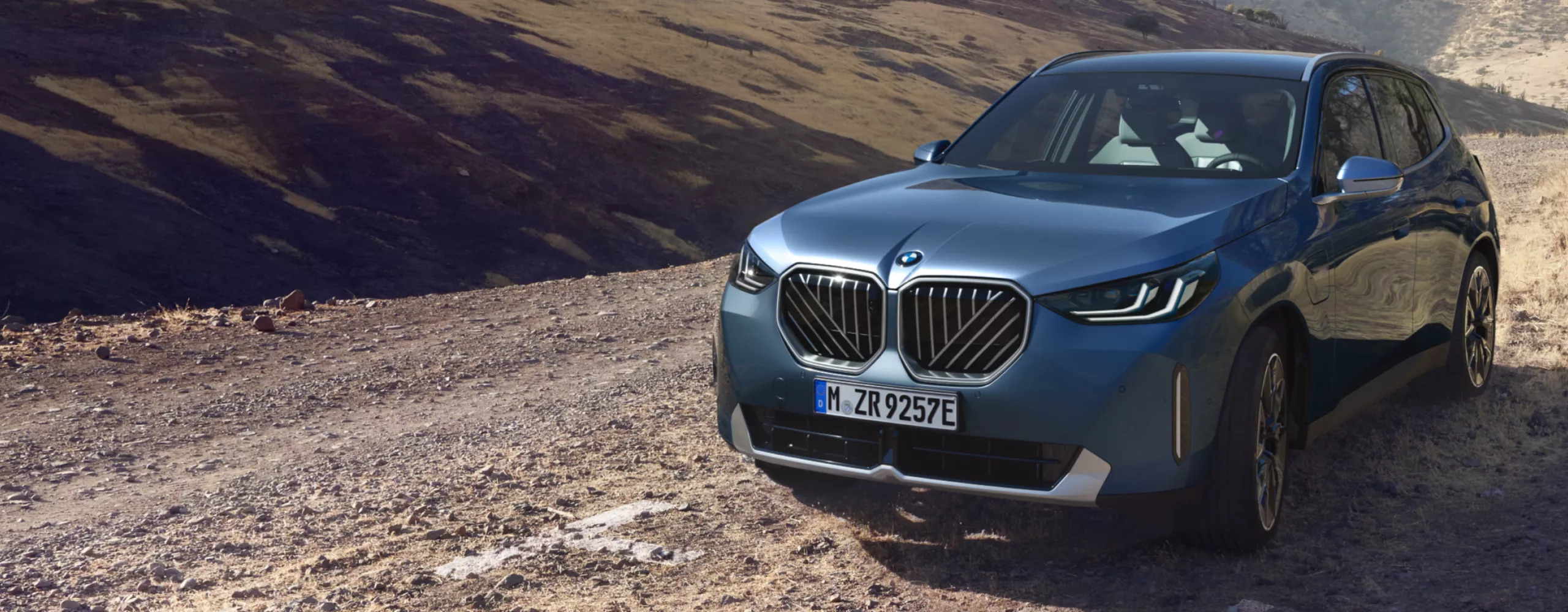 Un BMW X3 híbrido enchufable sobre un desierto rocoso y montañoso bajo el sol