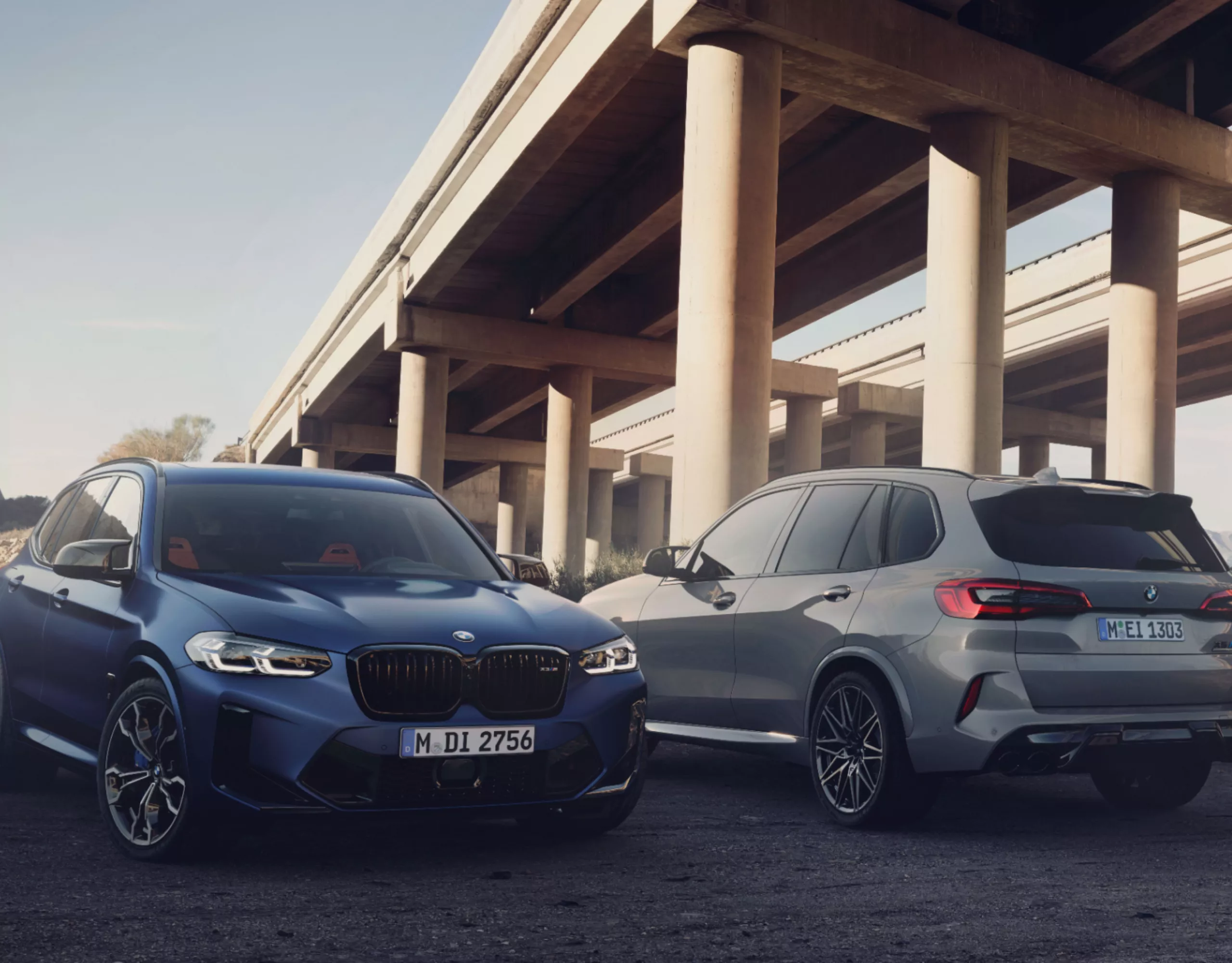 Dos SUV BMW de ocasión aparcados uno junto a otro bajo un puente de autopista