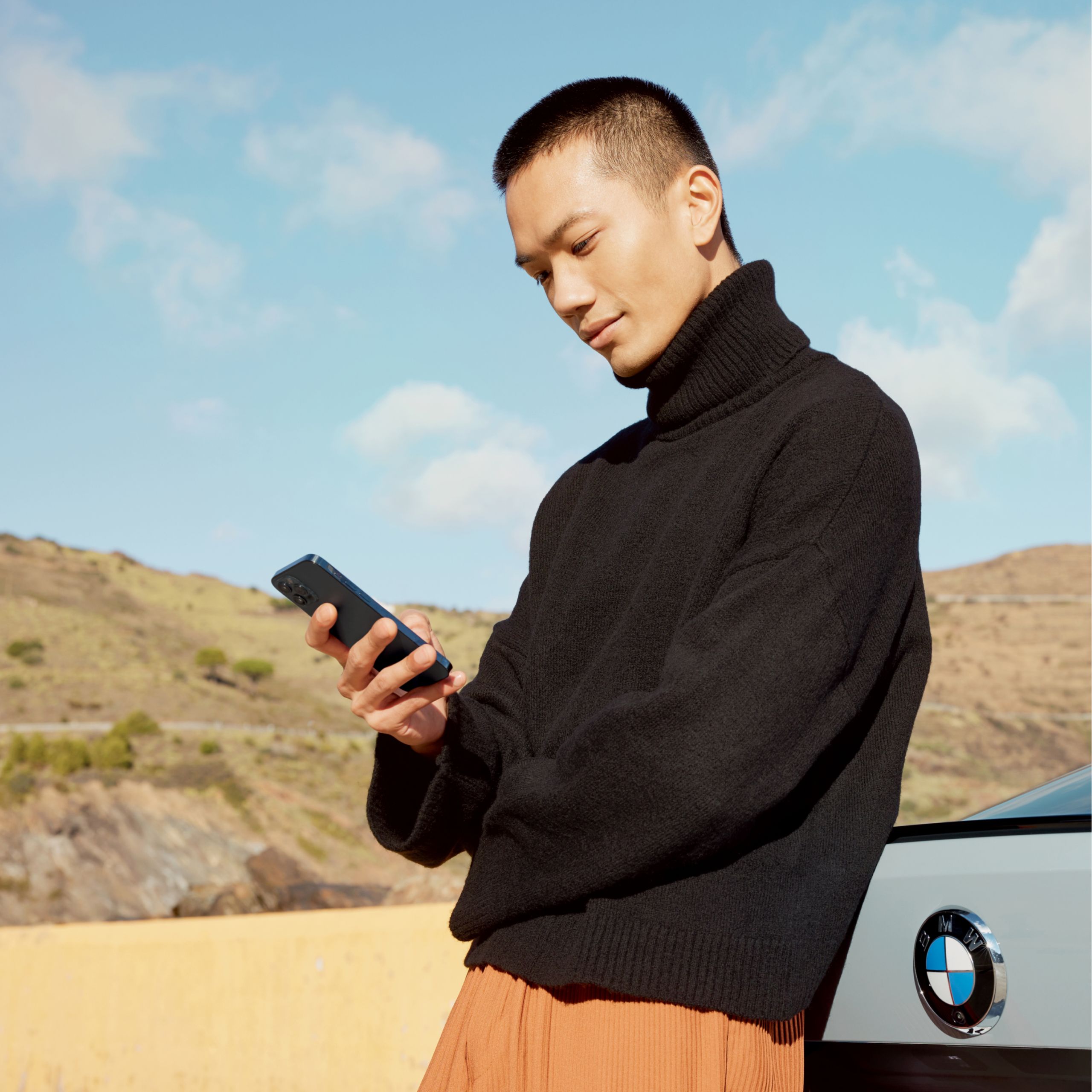 Mand i sort sweater holder en mobiltelefon.