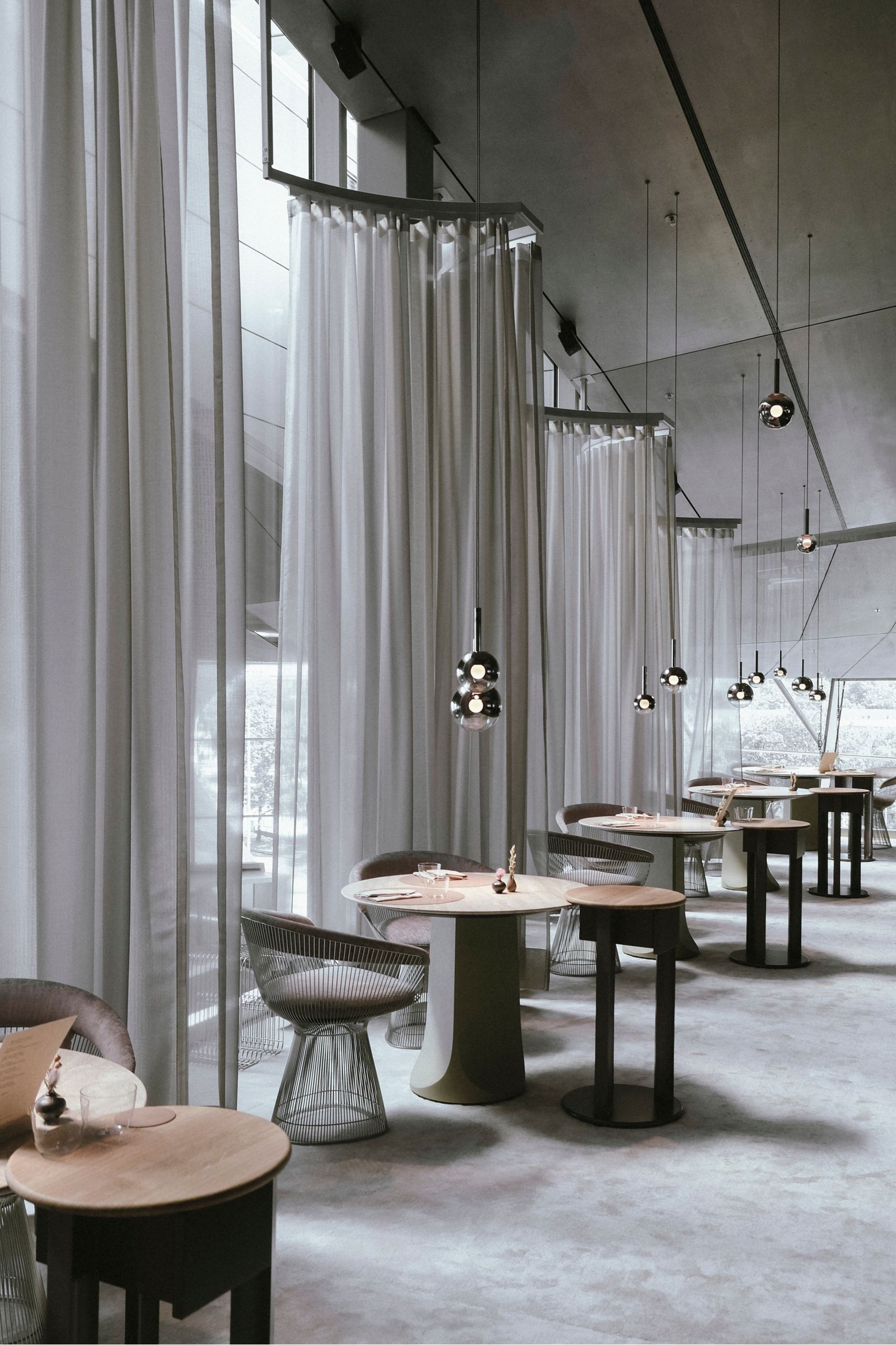 Exklusiv eingerichtetes, modernes Restaurant mit runden Tischen, eleganten Stühlen und sanfter Beleuchtung