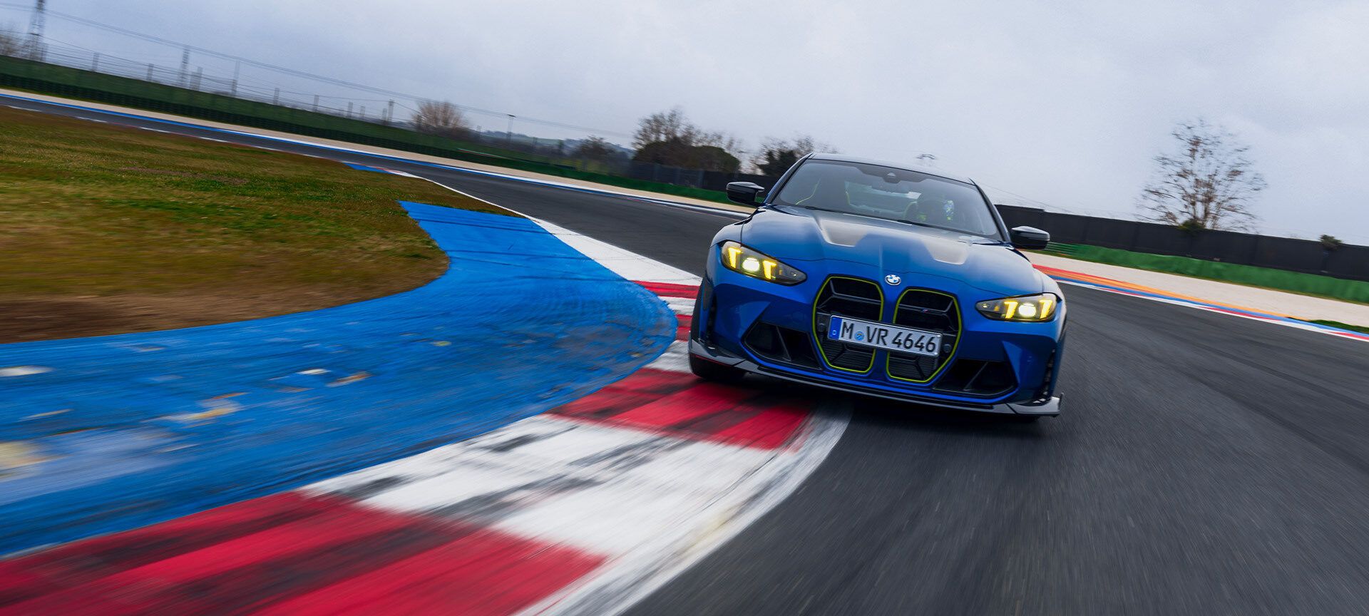 Zwei Männer in Werkstatt-Overalls heben die Motorhaube eines BMW an. Im Hintergrund ist ein abgedecktes Auto zu sehen