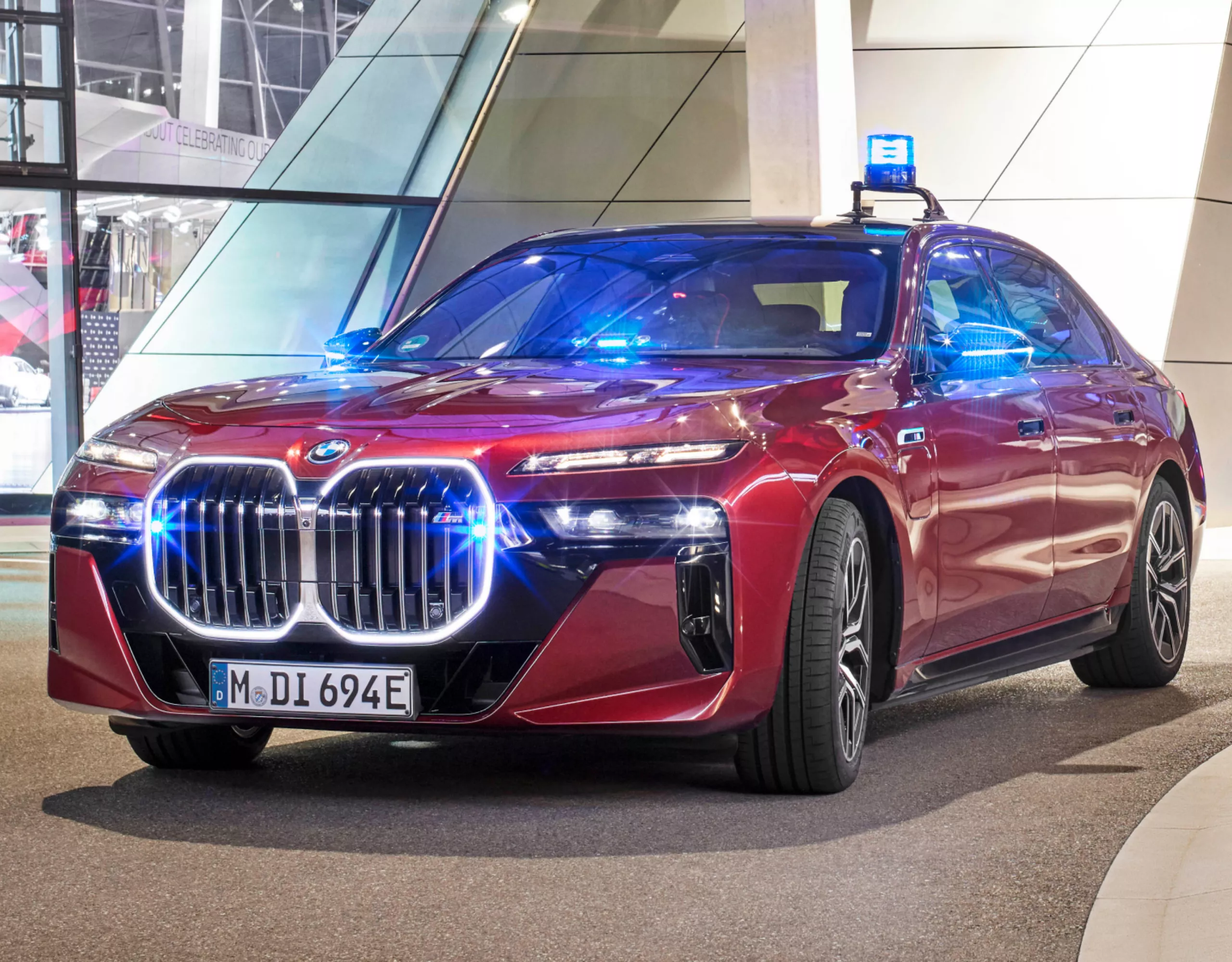 A BMW fire brigade vehicle parked in front of a modern building illuminated in pink and purple
