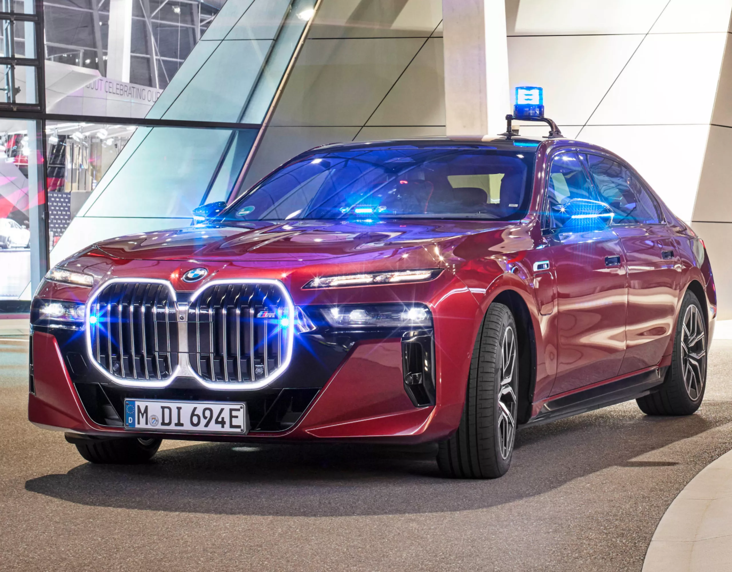 Voor de ingang van een helder verlicht modern gebouw staat een BMW interventievoertuig
