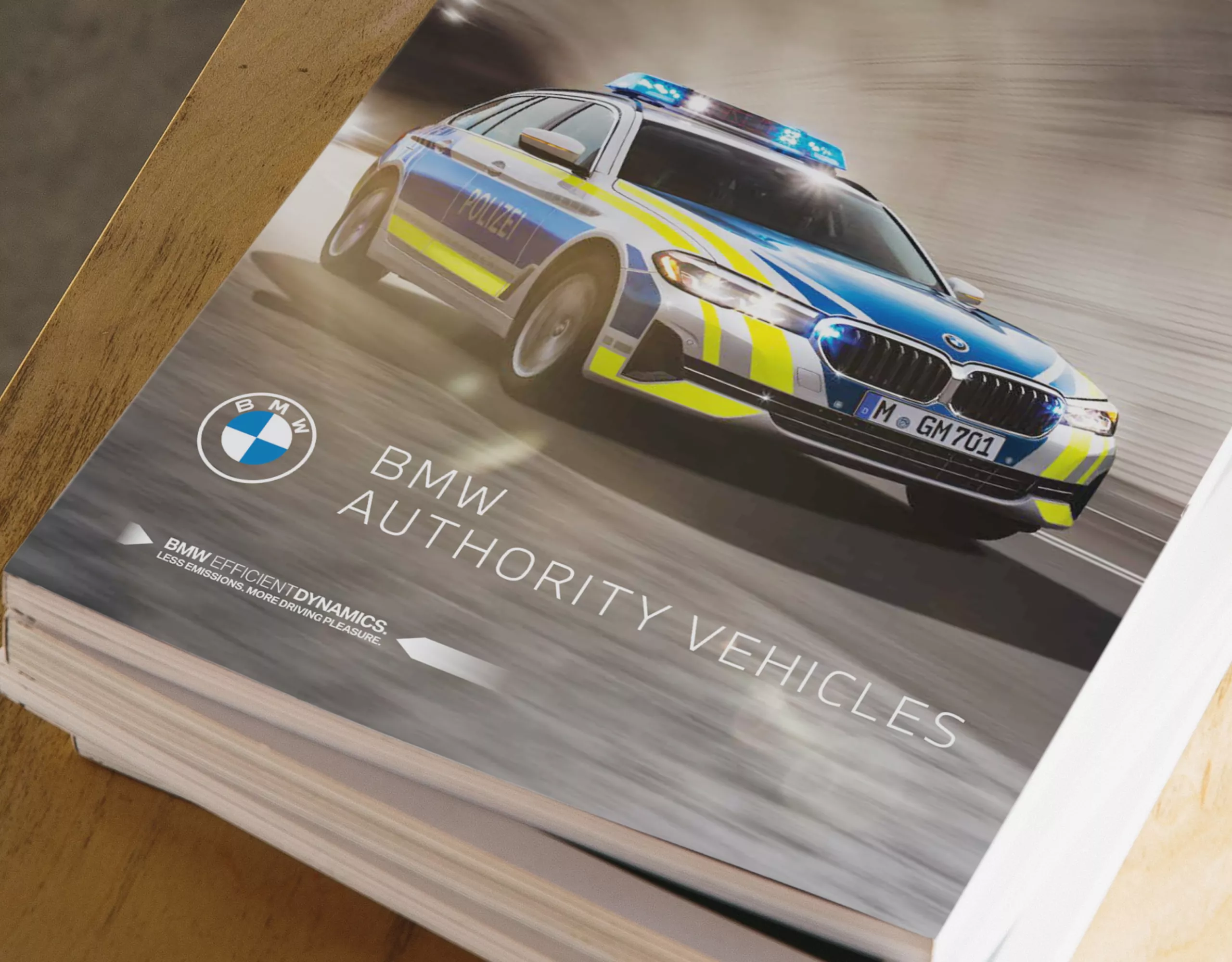 A pile of several brochures is lying on a wooden table