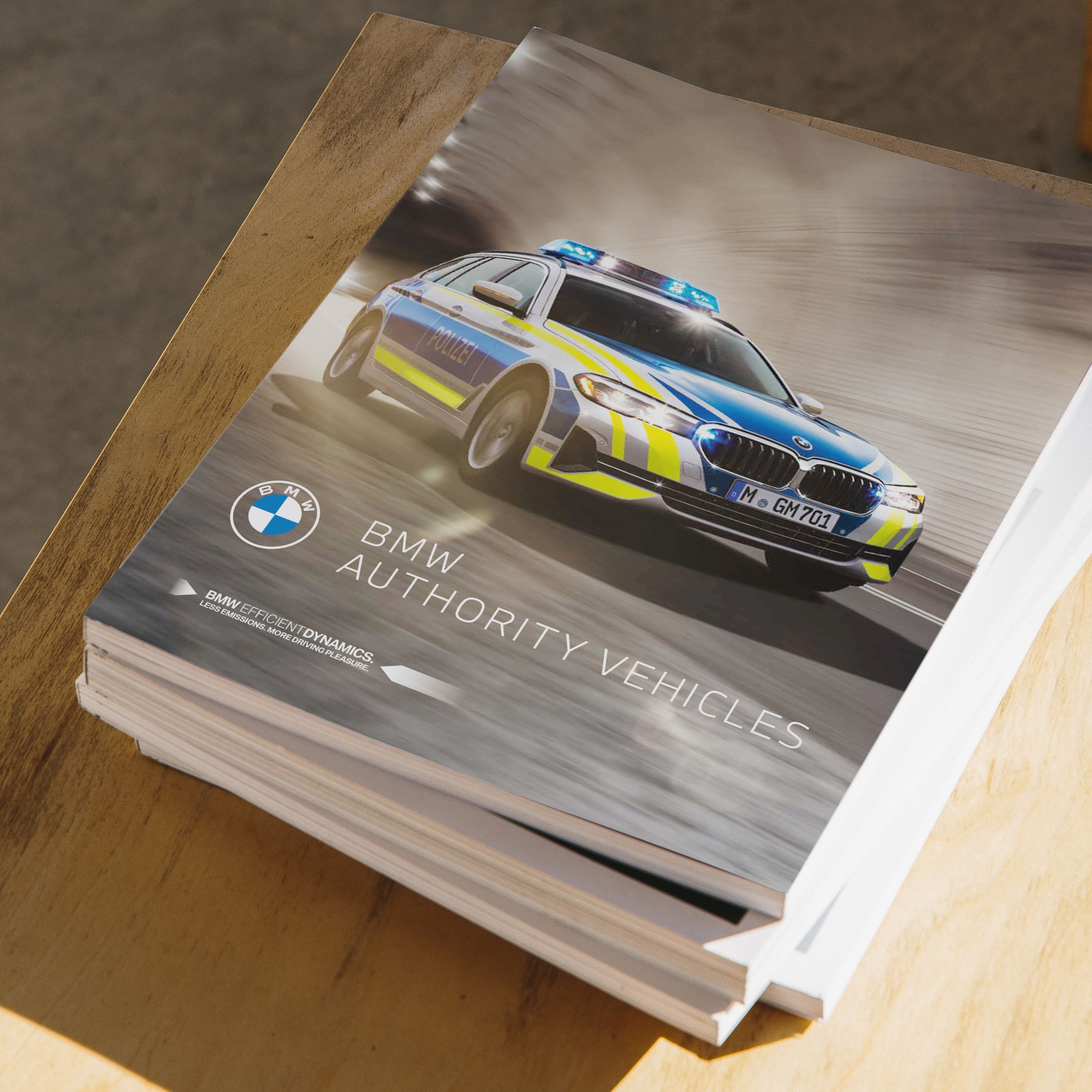 A pile of several brochures is lying on a wooden table