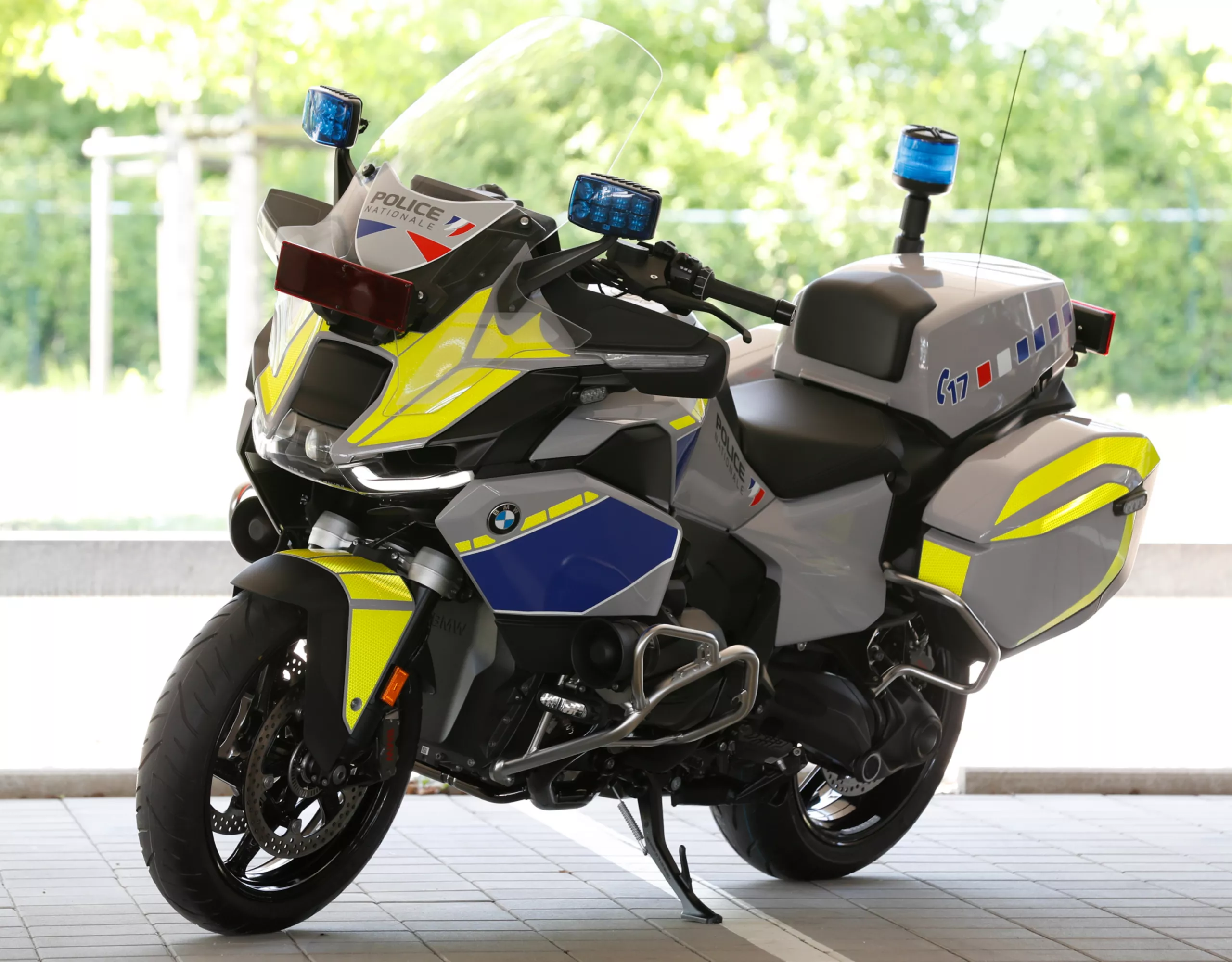 Ein BMW Einsatzmotorrad steht auf einem Parkplatz vor begrüntem Hintergrund