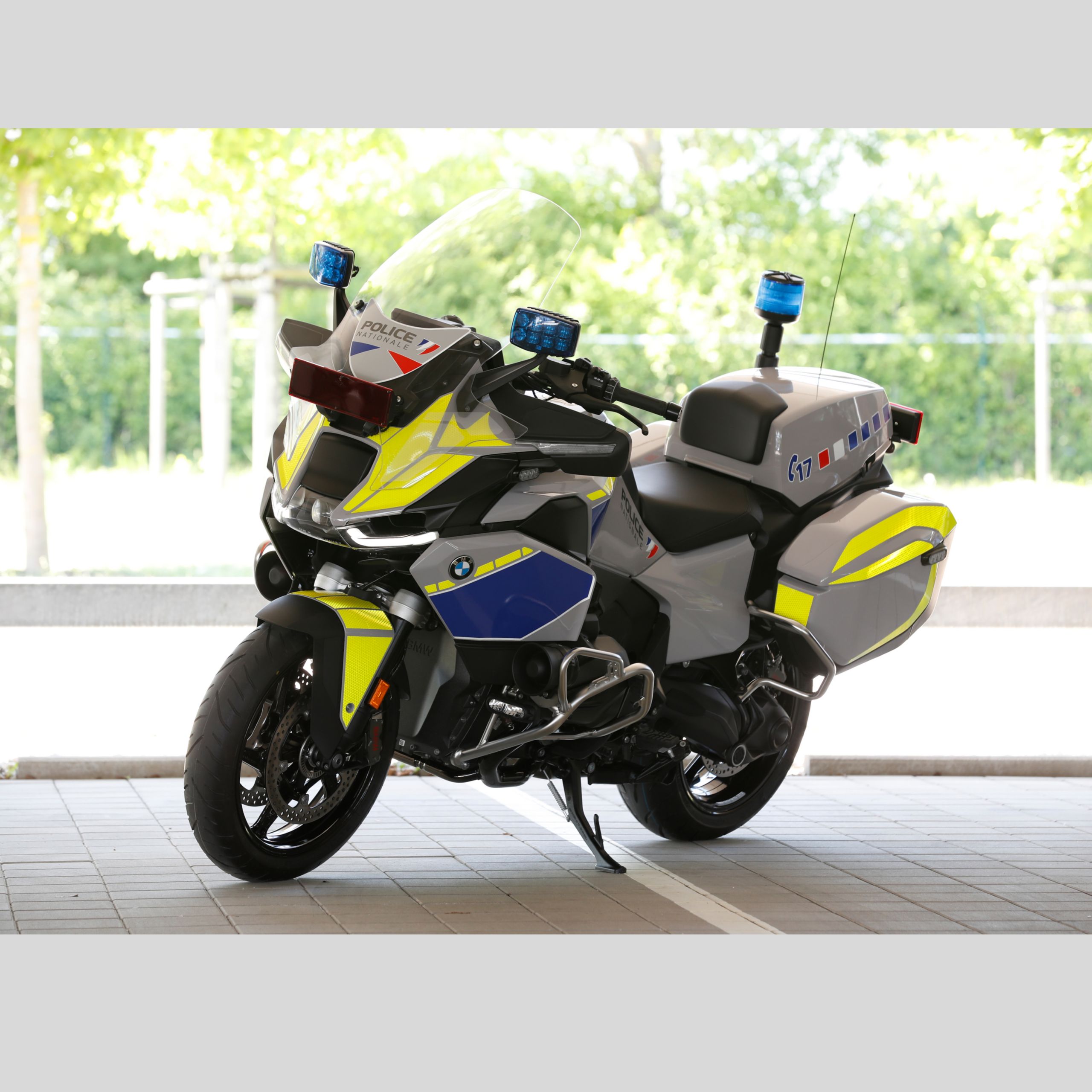 Ein BMW Einsatzmotorrad steht auf einem Parkplatz vor begrüntem Hintergrund