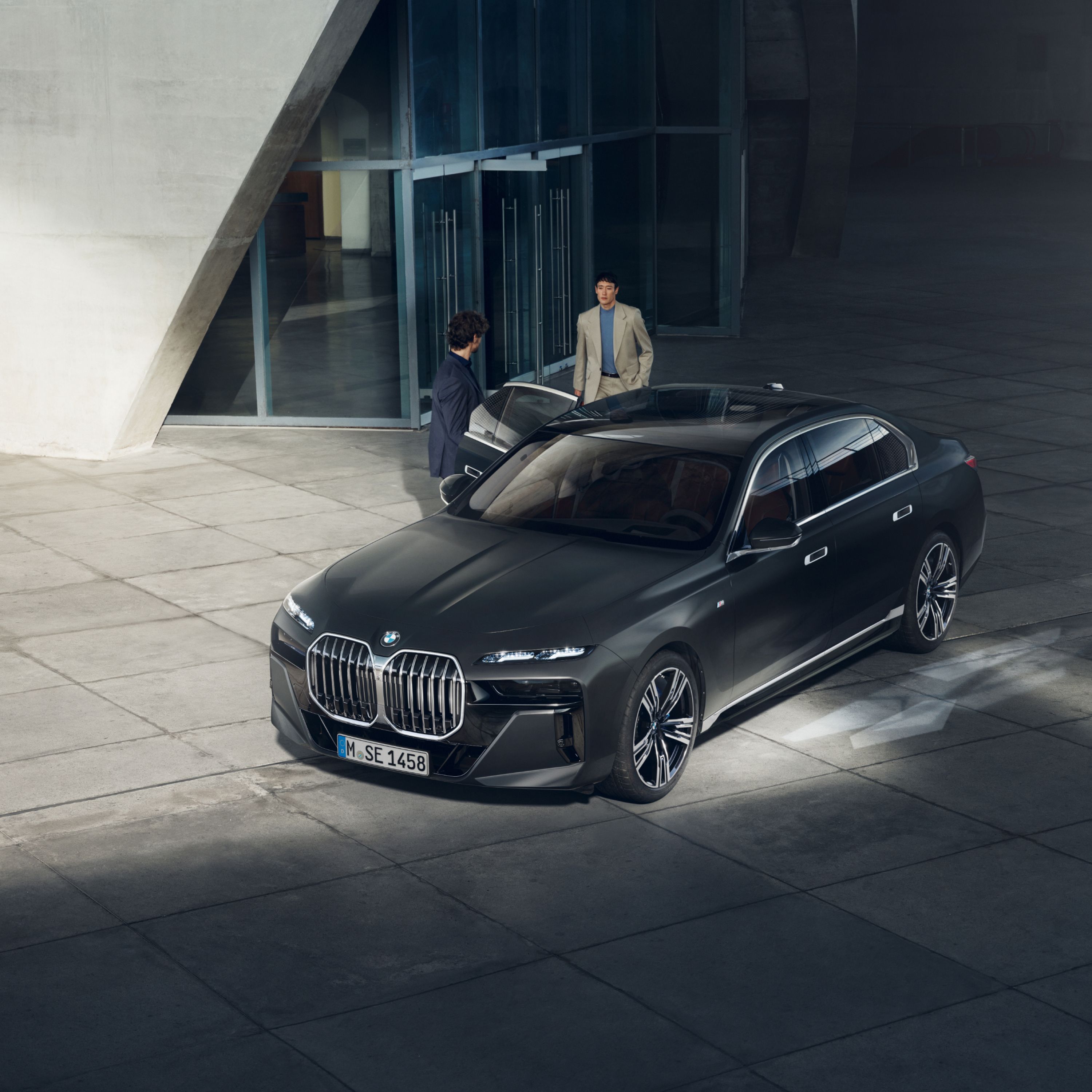 View from above of two people next to a BMW Diplomatic Vehicle in front of a building