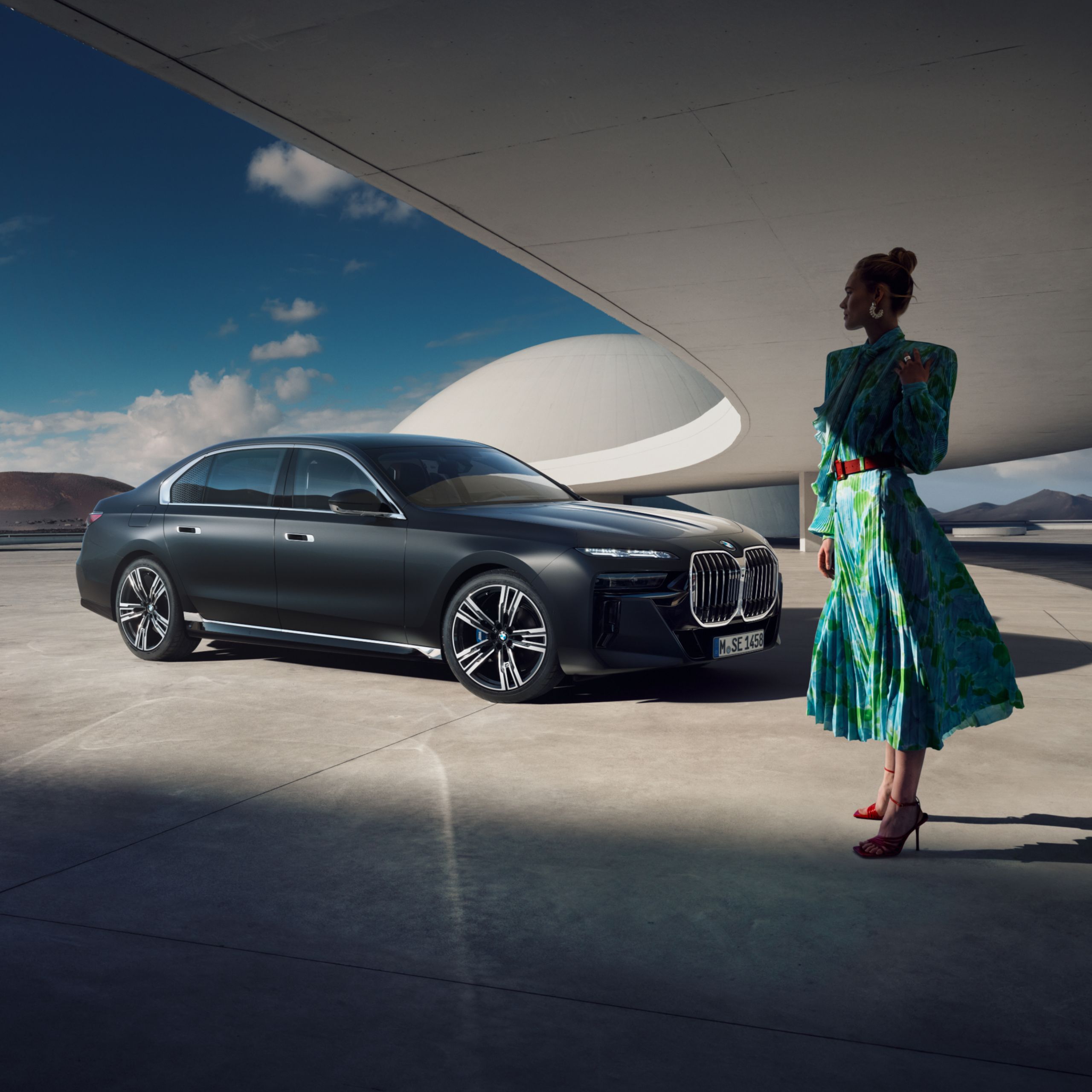 O femeie îmbrăcată elegant stă în fața unui BMW parcat