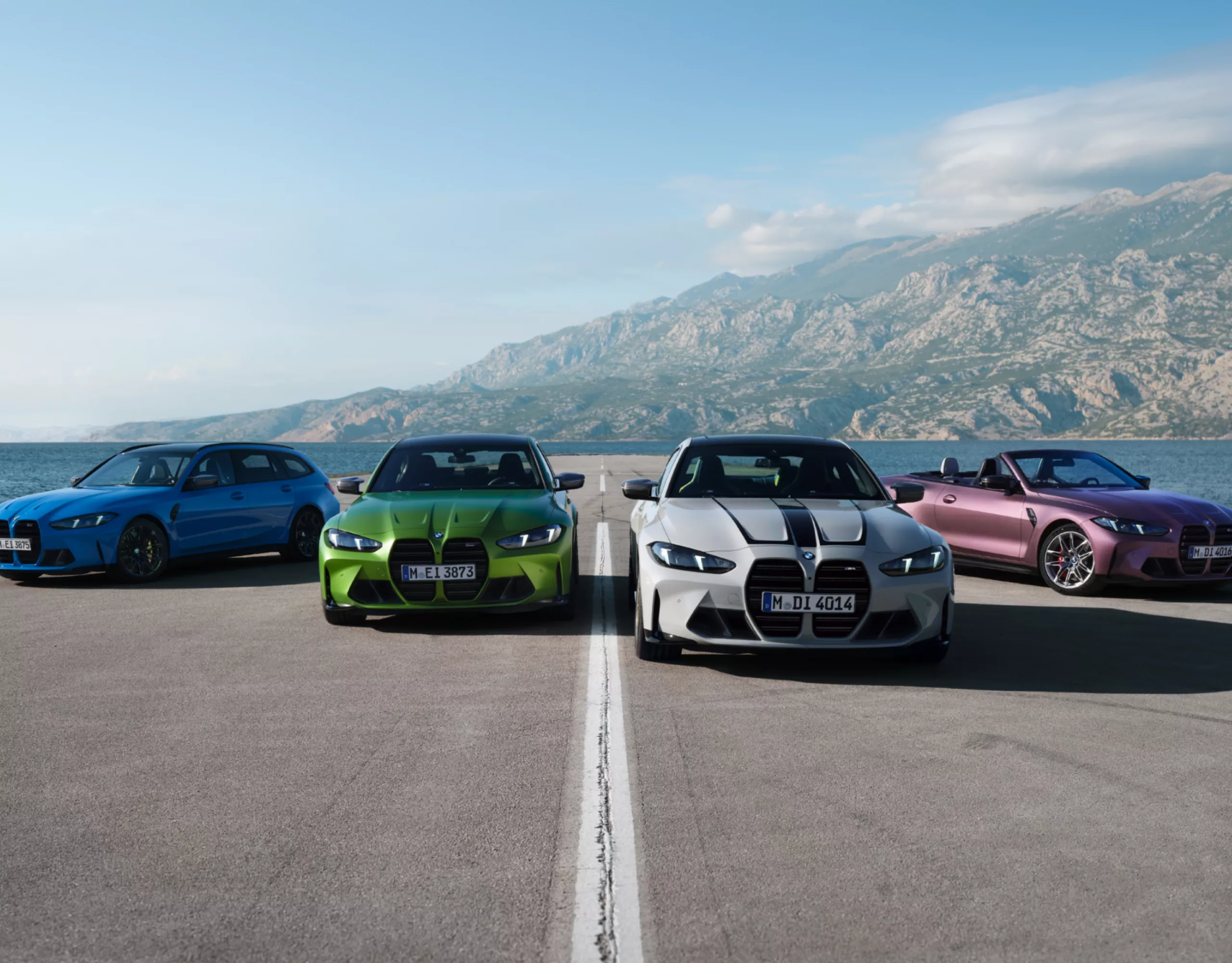 Vier sportliche BMW auf Parkplatz vor Kulisse mit Meer und Bergen