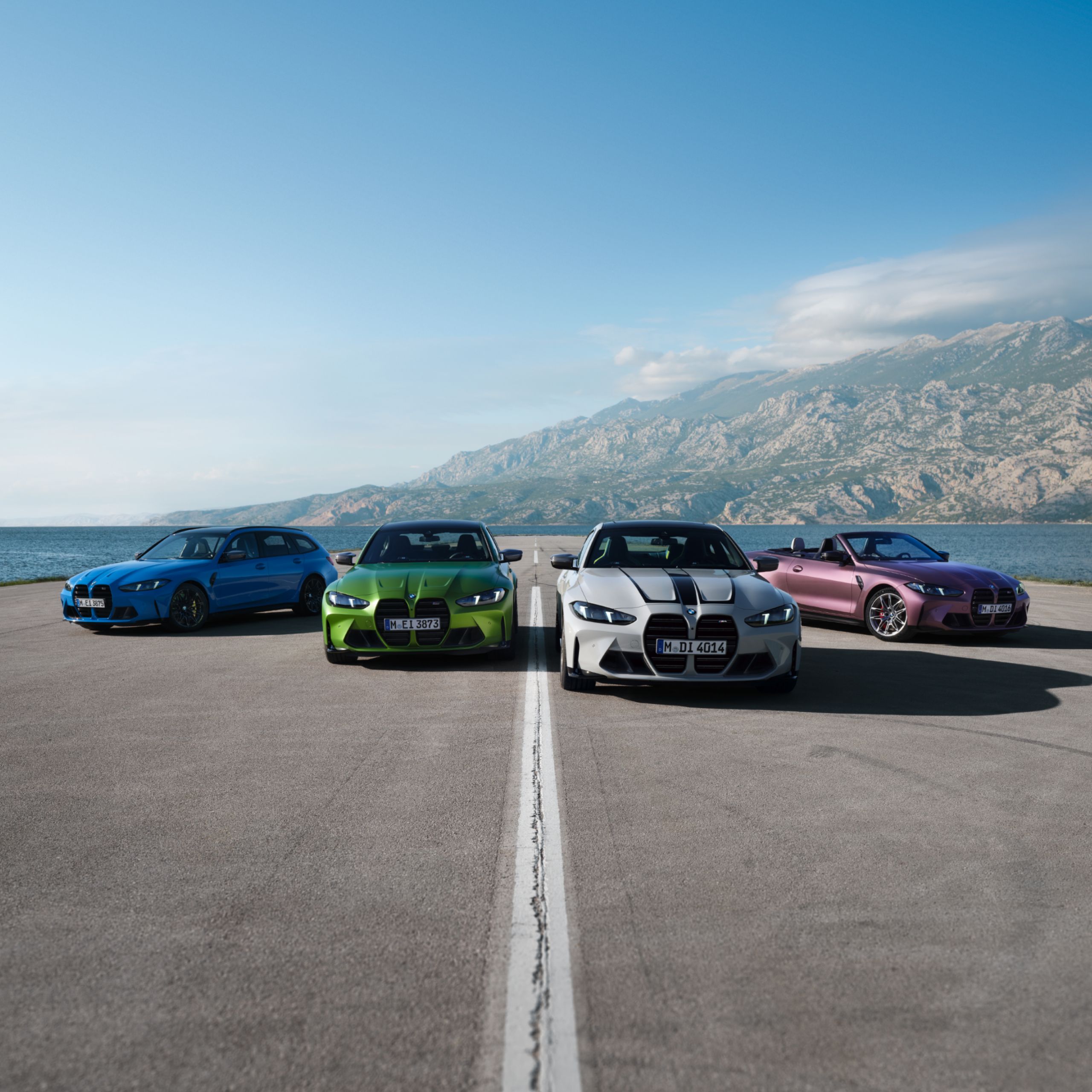 Cuatro BMW deportivos en un aparcamiento con mar y montañas como telón de fondo