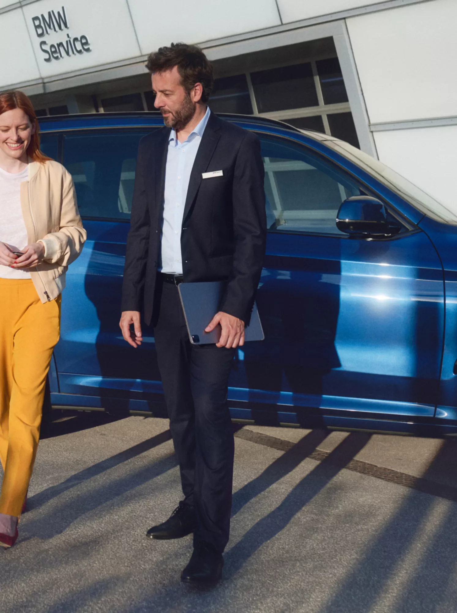 A man and woman in front of a BMW SUV with a BMW Service building in the background