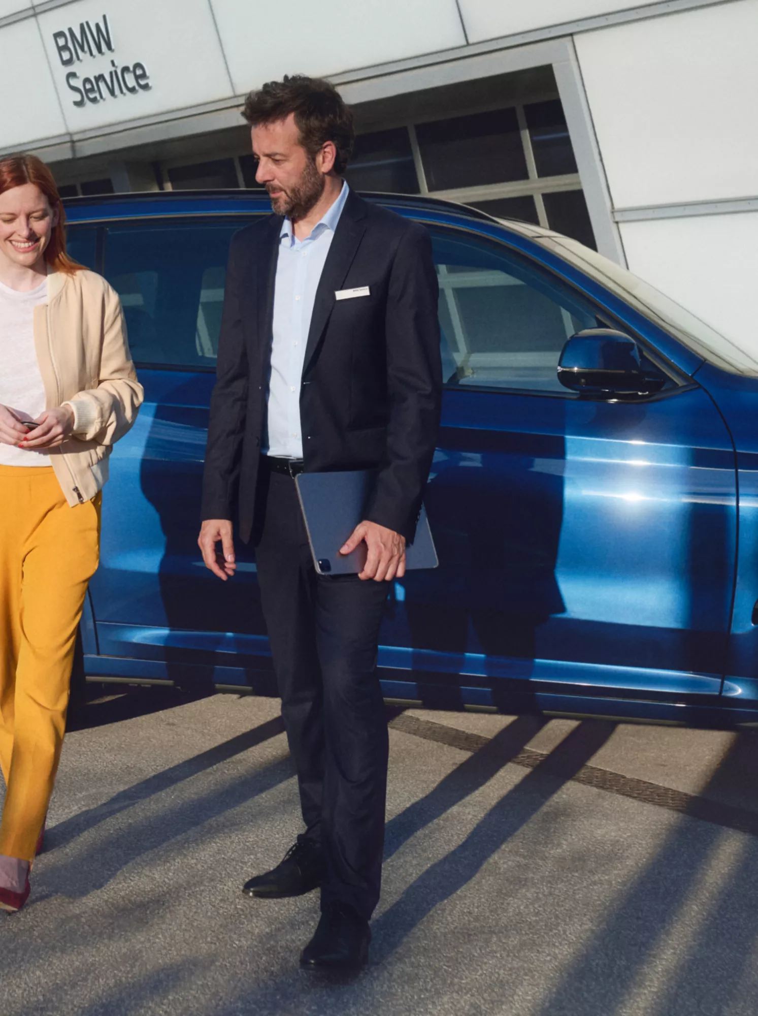 Mann und Frau vor BMW SUV vor BMW Service Gebäude