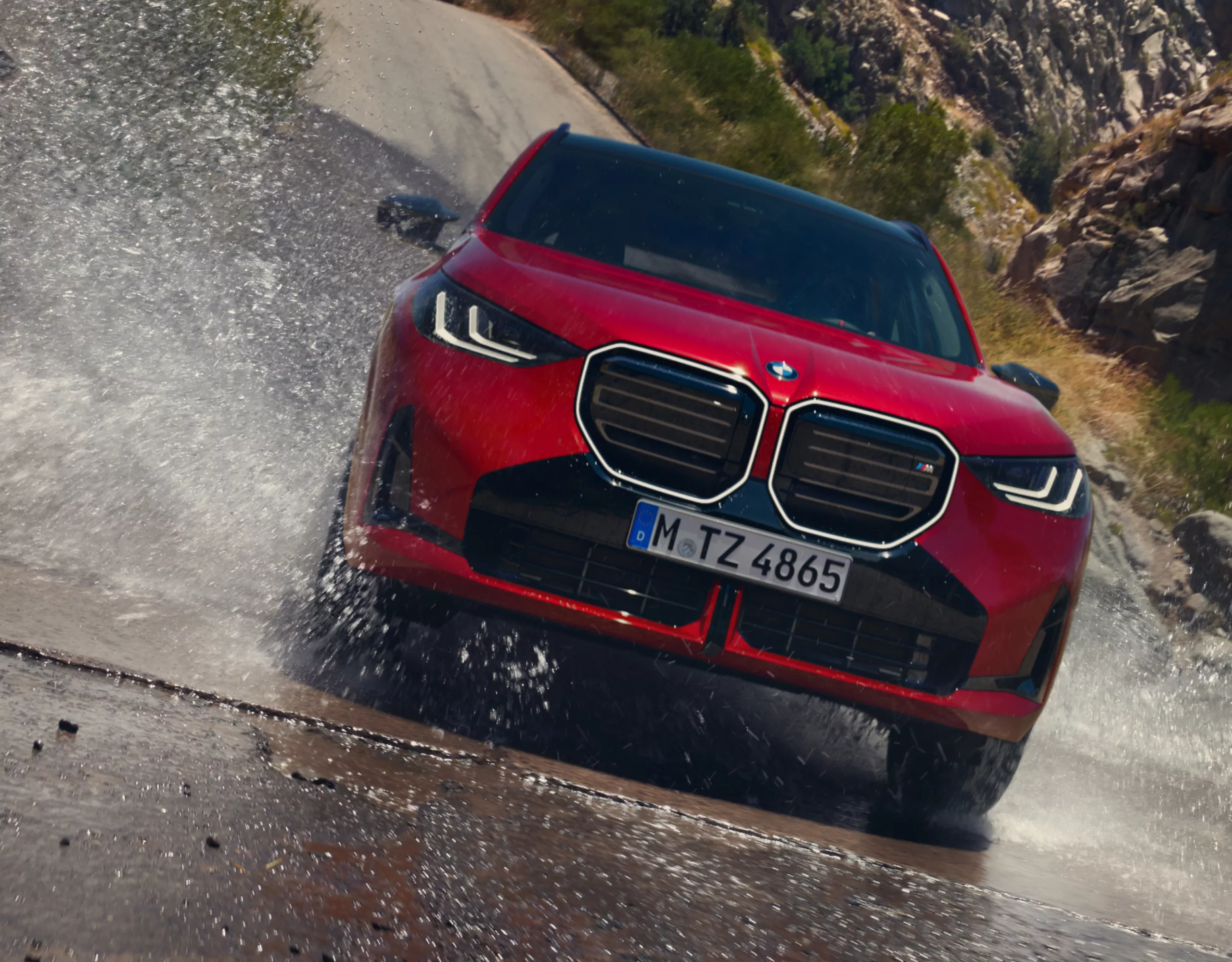 BMW SUV spritzt durch Pfütze auf Bergstraße
