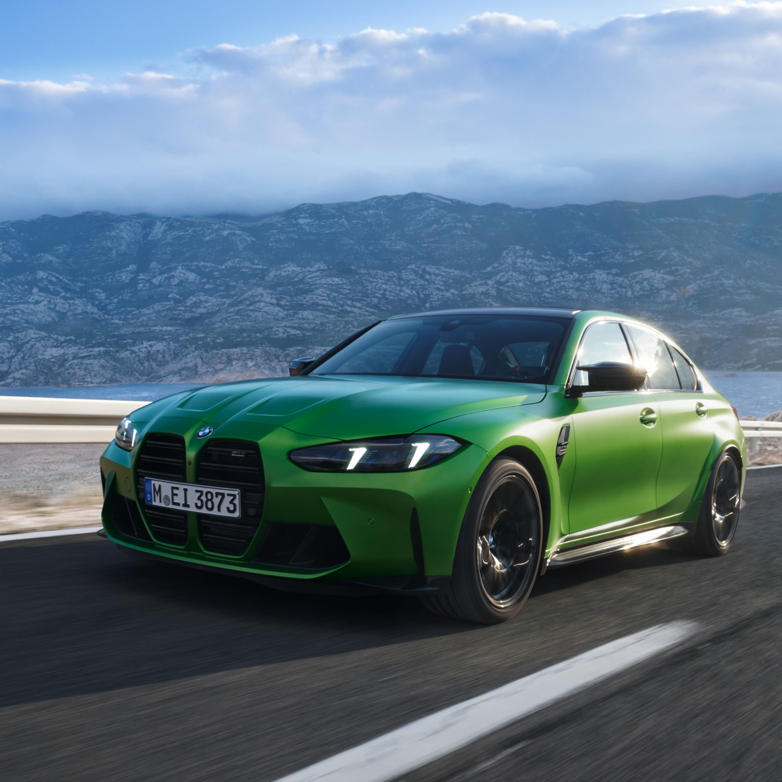 Un BMW en un aparcamiento con montañas y nubes espectaculares al fondo