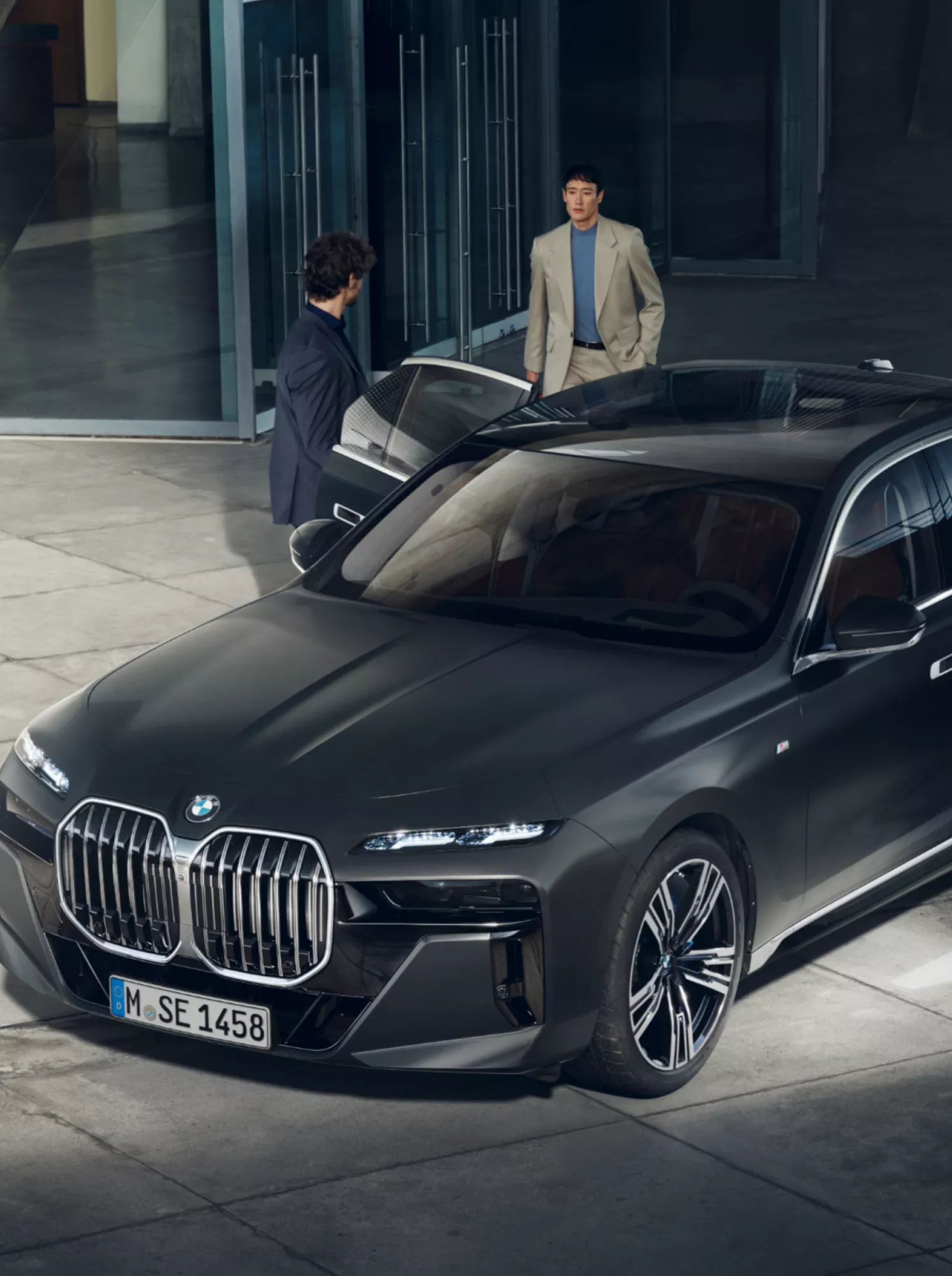 Draufsicht auf zwei Personen neben einem BMW Diplomatenfahrzeug vor einem Gebäude