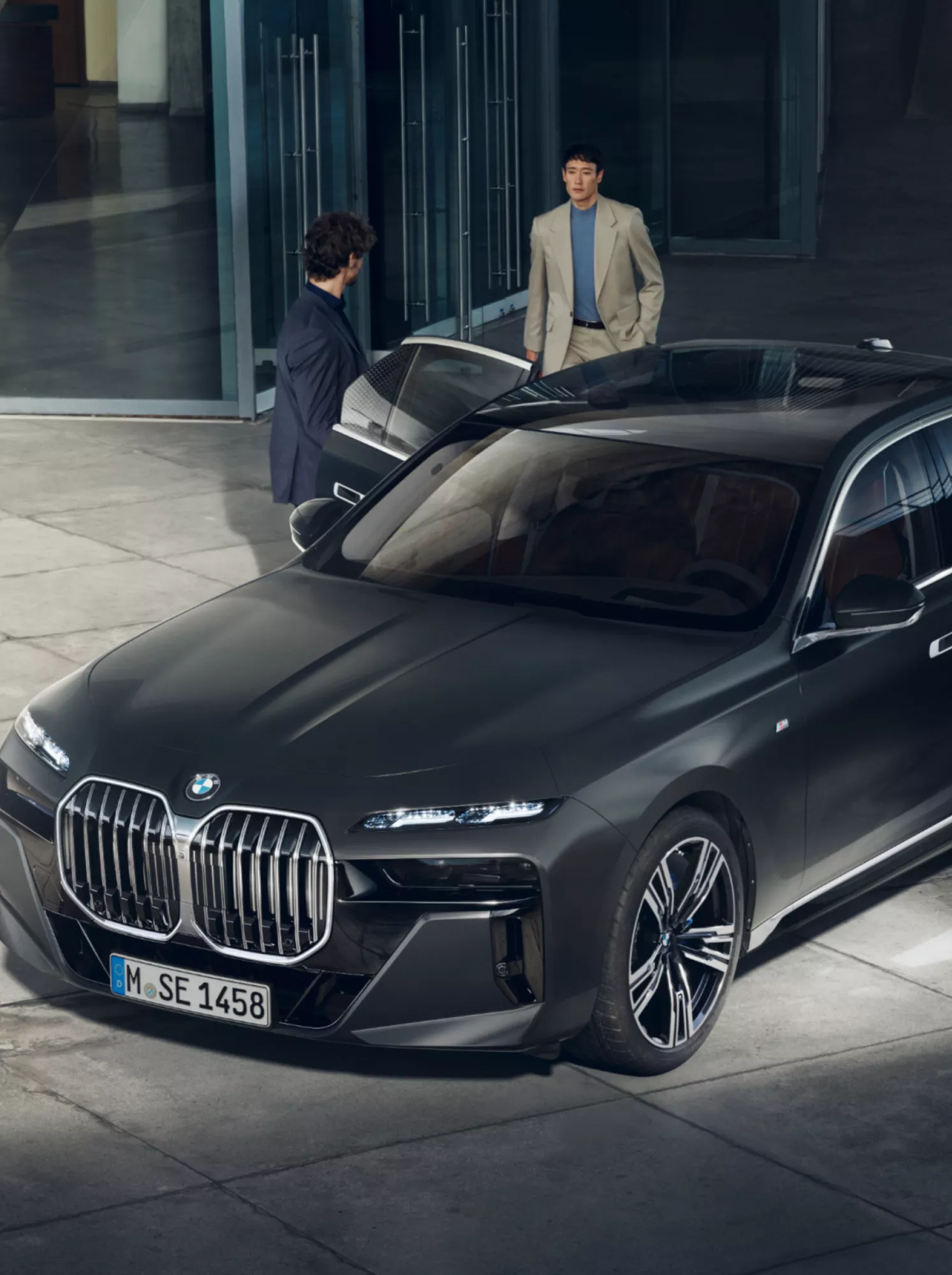 View from above of two people next to a BMW Diplomatic Vehicle in front of a building