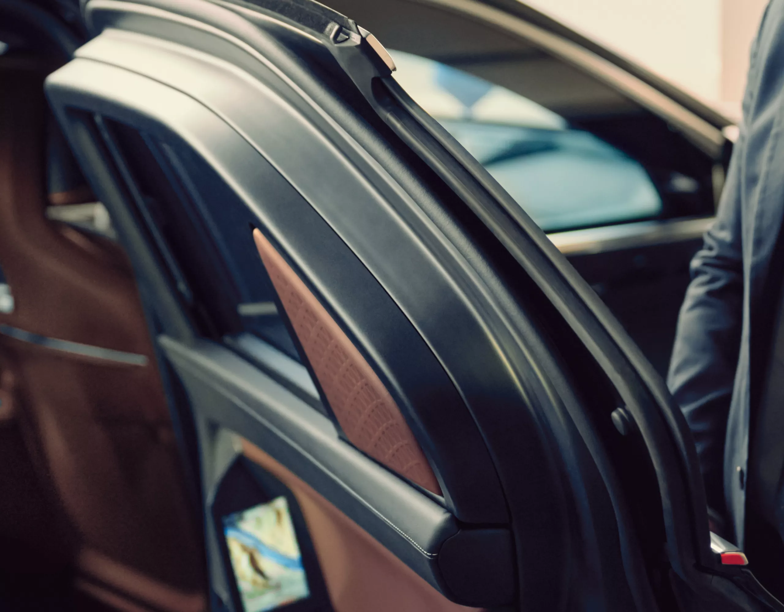 A close-up of a BMW door held open by a person in a suit