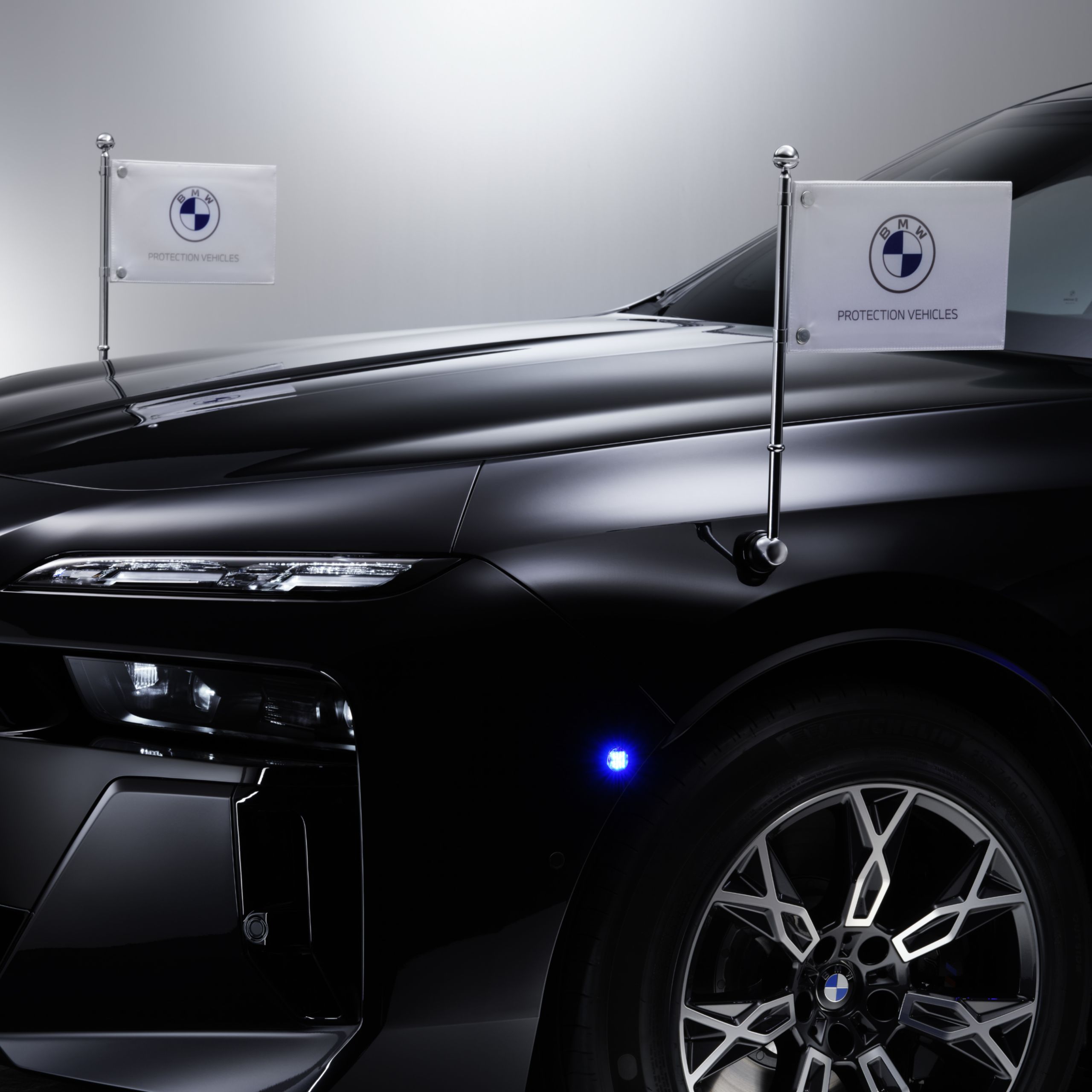 Egy BMW közeli képe elöl két zászlótartóval