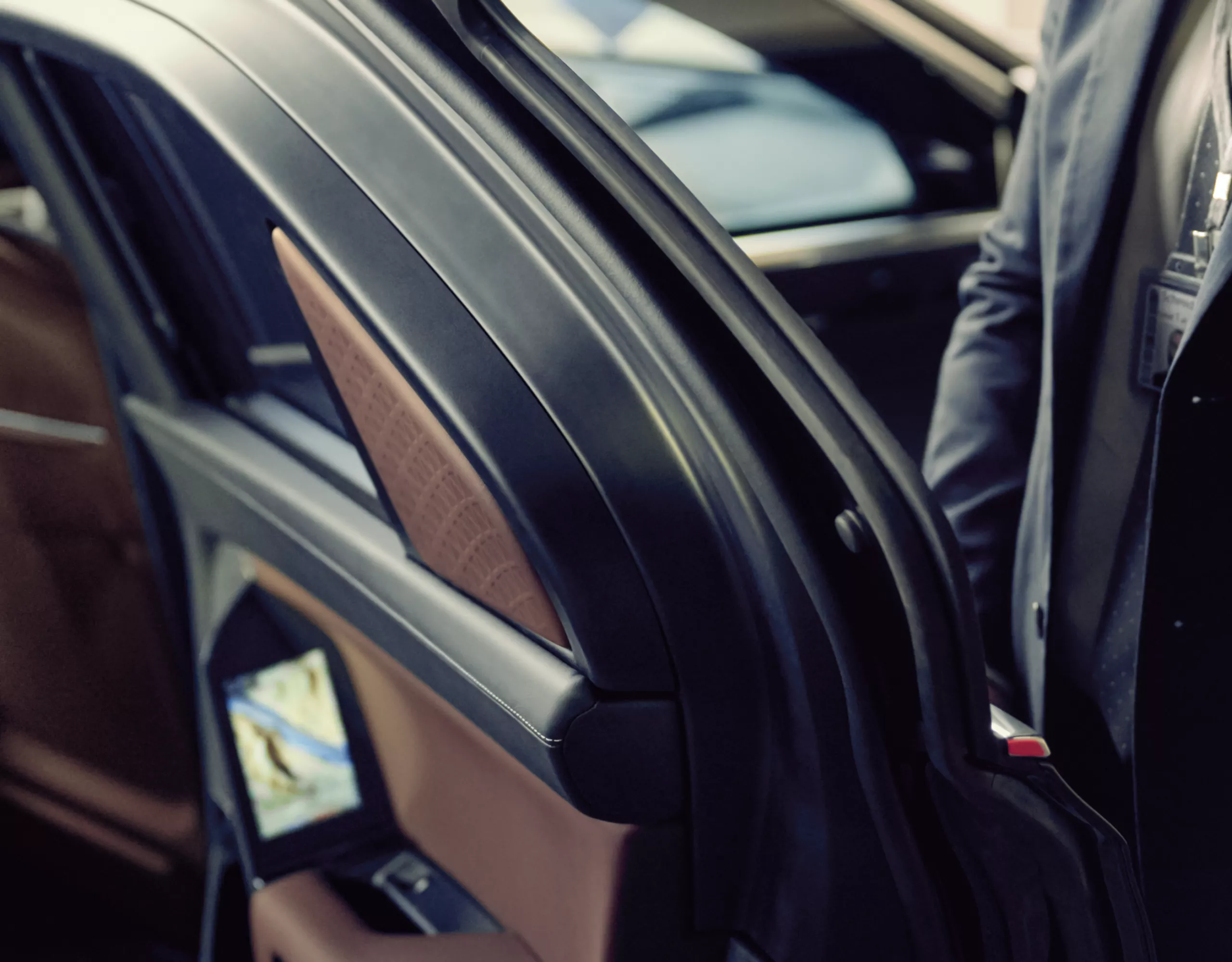 A close-up of a BMW door held open by a person in a suit