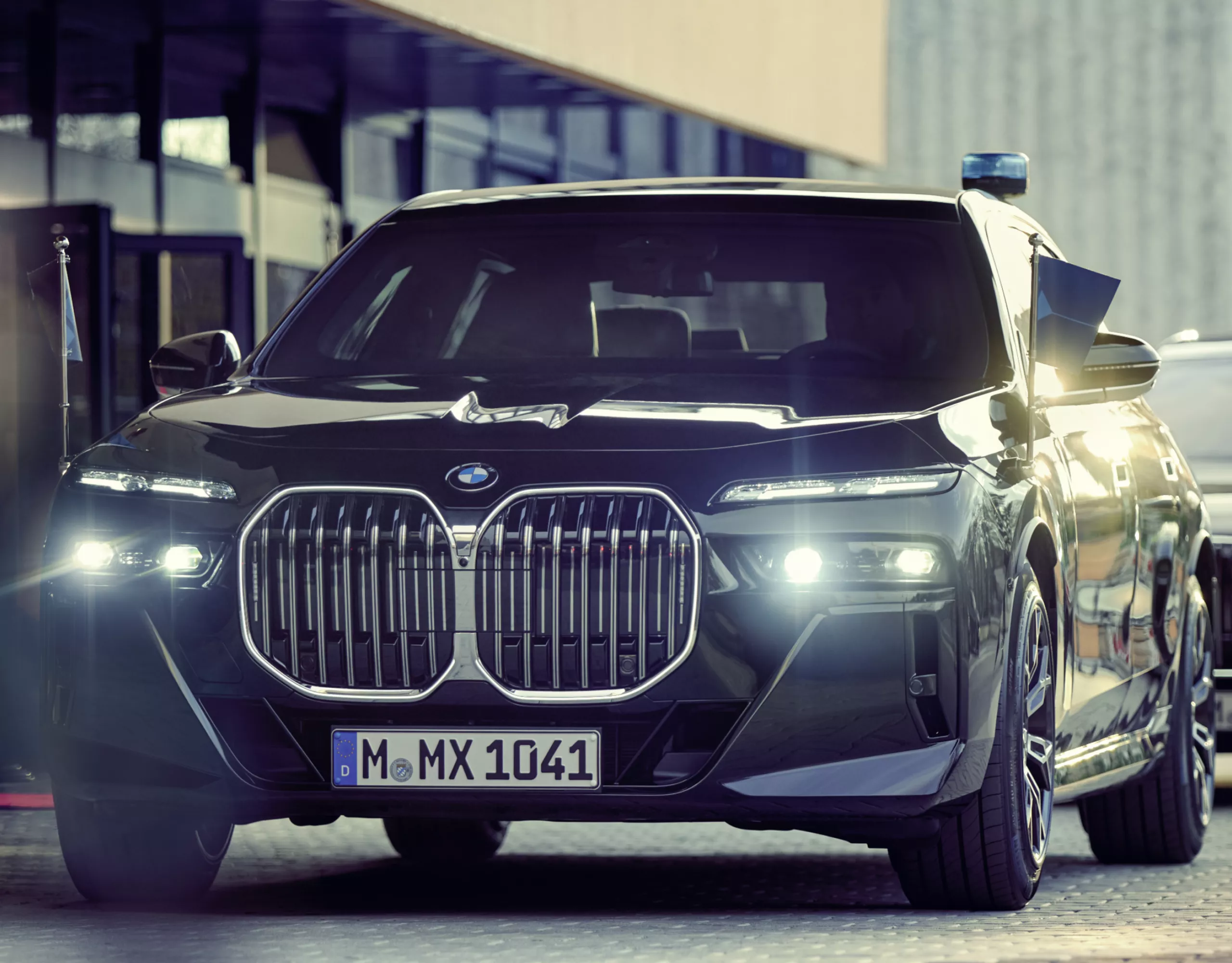 Ein BMW Sonderschutzfahrzeug mit Standartenhalter von vorn vor einem Gebäude
