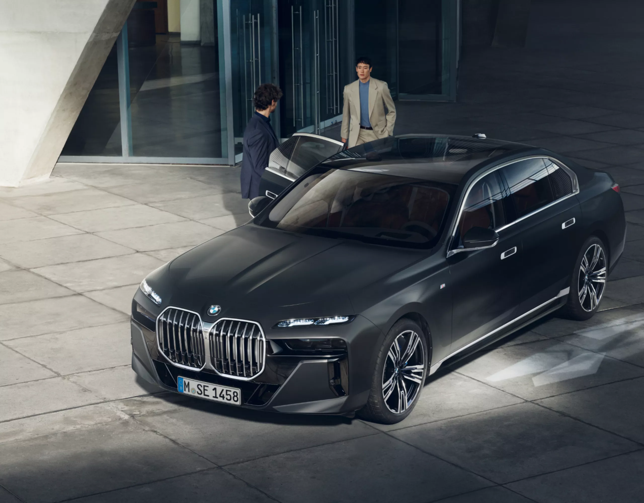 Draufsicht auf zwei Personen neben einem BMW Diplomatenfahrzeug vor einem Gebäude