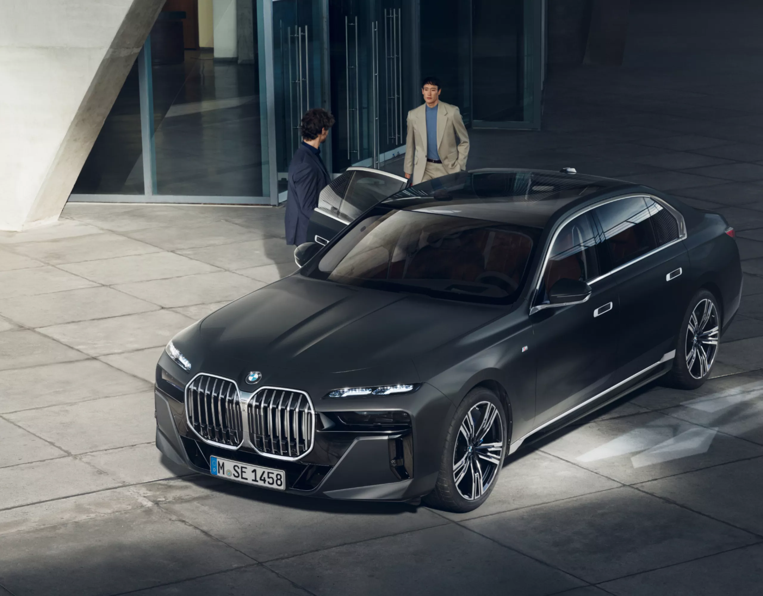 View from above of two people next to a BMW Diplomatic Vehicle in front of a building