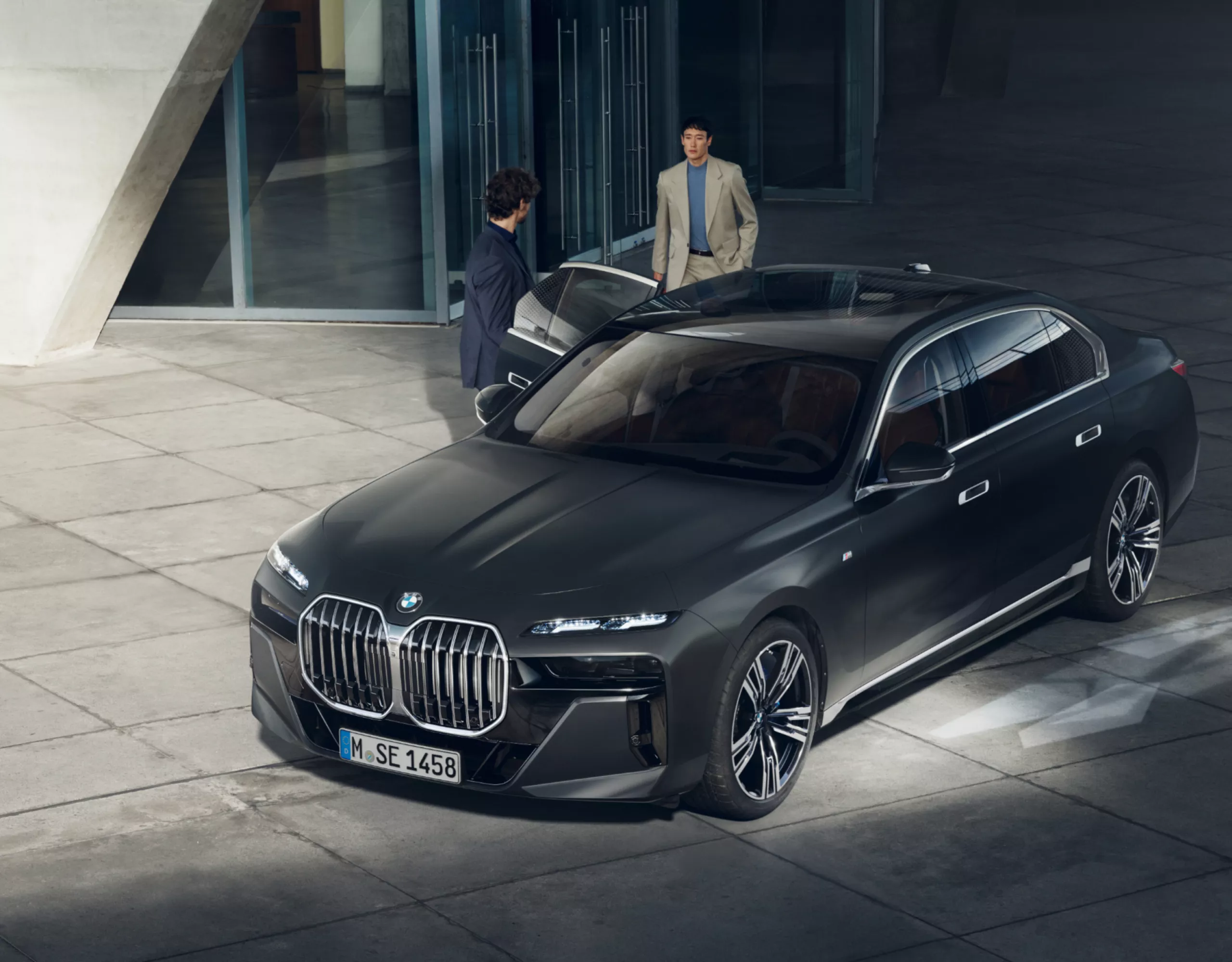 Draufsicht auf zwei Personen neben einem BMW Diplomatenfahrzeug vor einem Gebäude